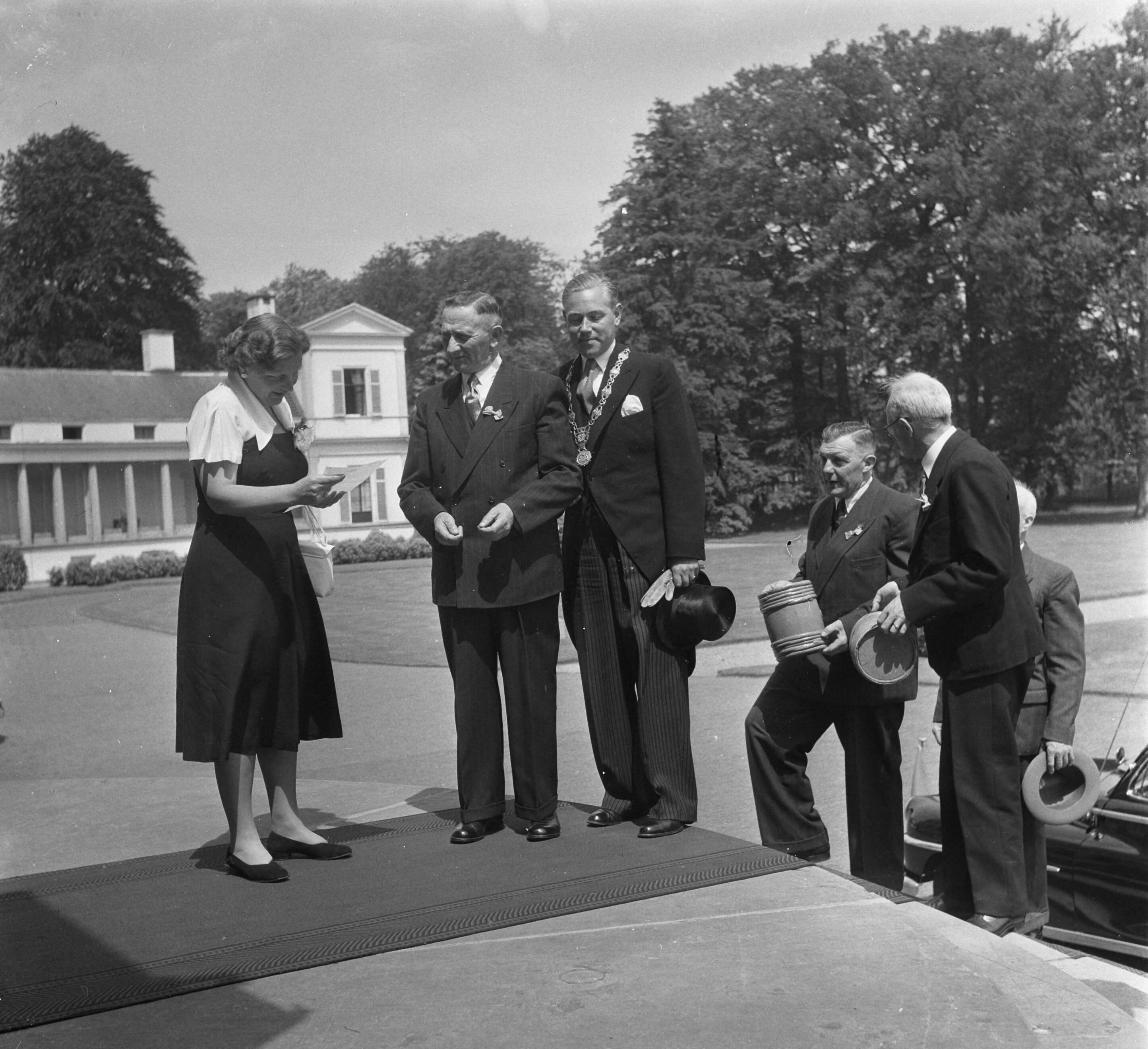 Aanbieding Koninginneharing op Soestdijk — Aanbieding Koninginneharing door de Rijksopperkeurmeester aan koningin Juliana op paleis Soestdijk. De koningin leest het keuringsrapport. Vlnr. Rijkopperkeurmeester W. Don, burgemeester van Vlaardingen J. Heusdens, Schipper G. van der Snoek van de VL 74 "Hendrika en Adriana" die de haring heeft aangevoerd met het vaatje en de de reder van de N.V. Zeevisserij en Haringhandel v/h A. Verboom met een ander vaatje (rechts) — Foto: Noske, J.D. / Anefo. Licentie: Set B: Rechtenvrij / Publiek Domein. Bron: Nationaal Archief. http://hdl.handle.net/10648/a8faeafa-d0b4-102d-bcf8-003048976d84