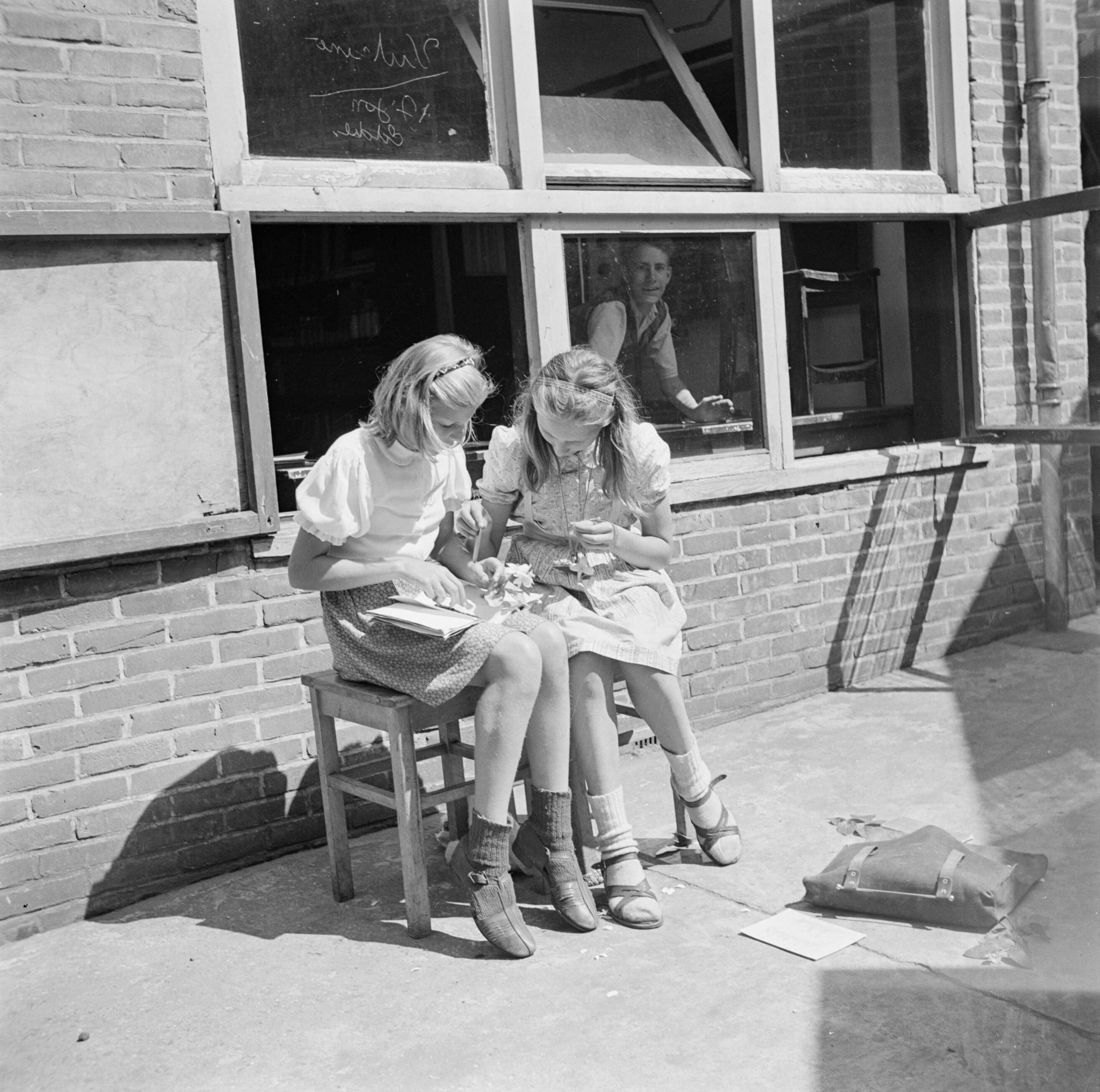 De prinsessen Beatrix en Irene op de Werkplaats Kindergemeenschap van Kees Boeke te Bilthoven — Leerlingen zitten op het terras te werken — Foto: Poll, Willem van de. Licentie: Set B: Rechtenvrij / Publiek Domein. Bron: Nationaal Archief. http://hdl.handle.net/10648/aee8070e-d0b4-102d-bcf8-003048976d84