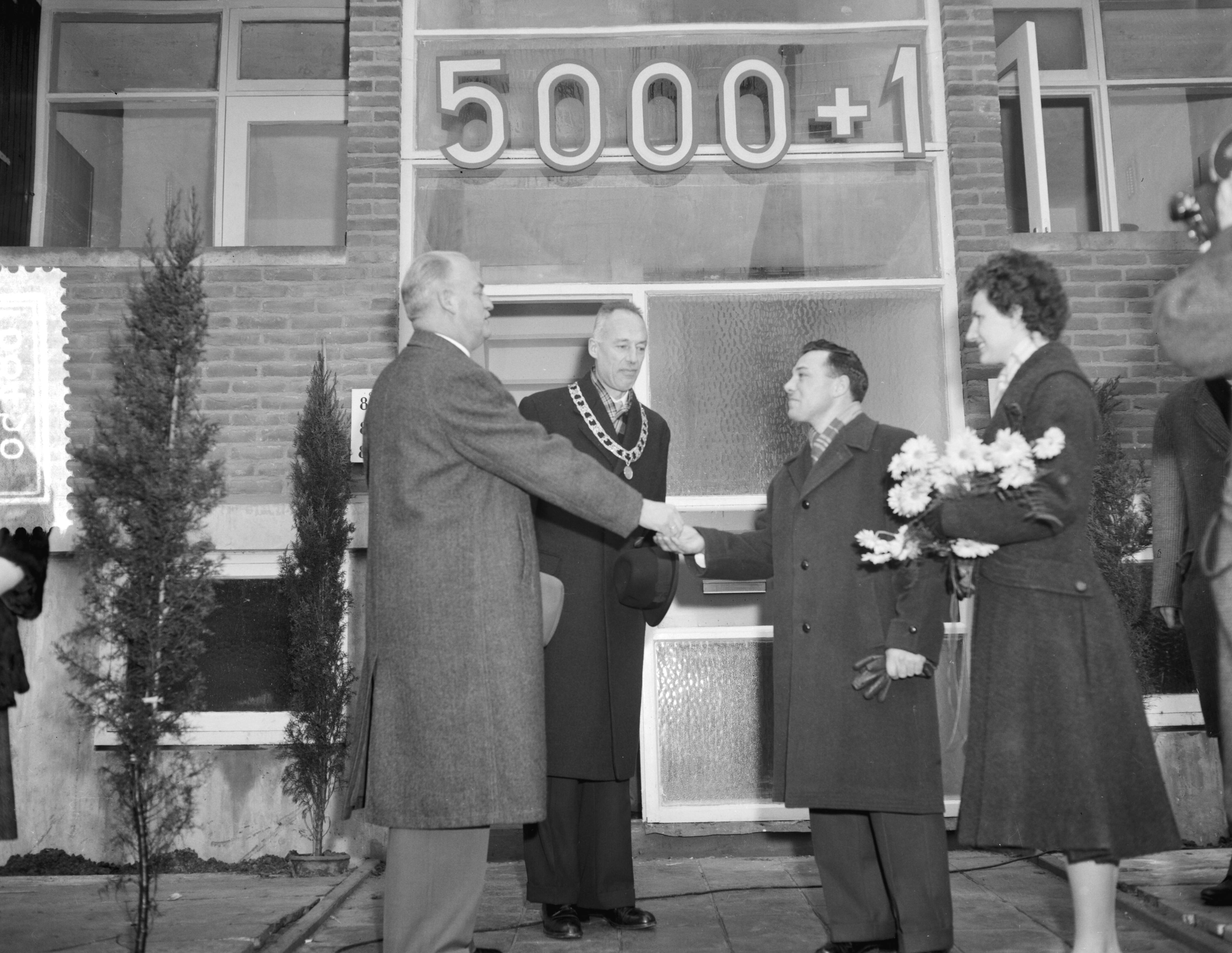 Fotocollectie Anefo — 5000ste na-oorlogse woning te Leeuwarden gereed gekomen. Betreft Beukenstraat nr. 6 in de buurt Heechterp, bewoners de familie Burger. Ir. D. Visser, hoofdingenieur-directeur van Volkshuisvesting en Bouwnijverheid in Friesland, overhandigt de sleutel. Naast hem burgemeester A.A.M. van der Meulen — Foto: Rossem, Wim van / Anefo. Licentie: Set B: Rechtenvrij / Publiek Domein. Bron: Nationaal Archief. http://hdl.handle.net/10648/a9a2bf3c-d0b4-102d-bcf8-003048976d84