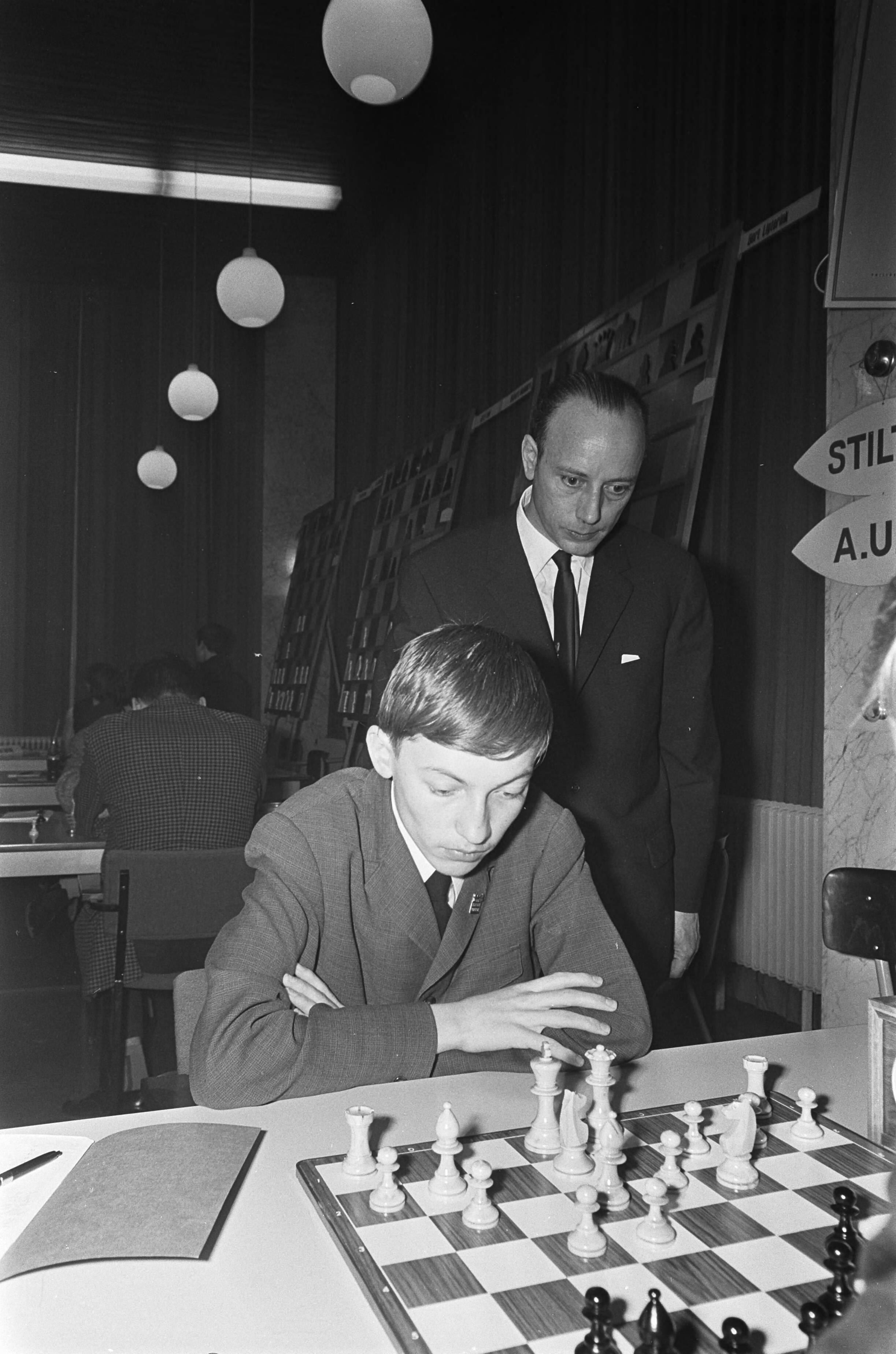 Fotocollectie Anefo — Zesde Niemeyer Jeugdschaaktoernooi te Groningen. Piet Roozenburg kijkt bij de jongste schaker, de Rus Anatoli Karpov — Foto: Nijs, Jac. de / Anefo. Licentie: Set B: Rechtenvrij / Publiek Domein. Bron: Nationaal Archief. http://hdl.handle.net/10648/ab30ec70-d0b4-102d-bcf8-003048976d84