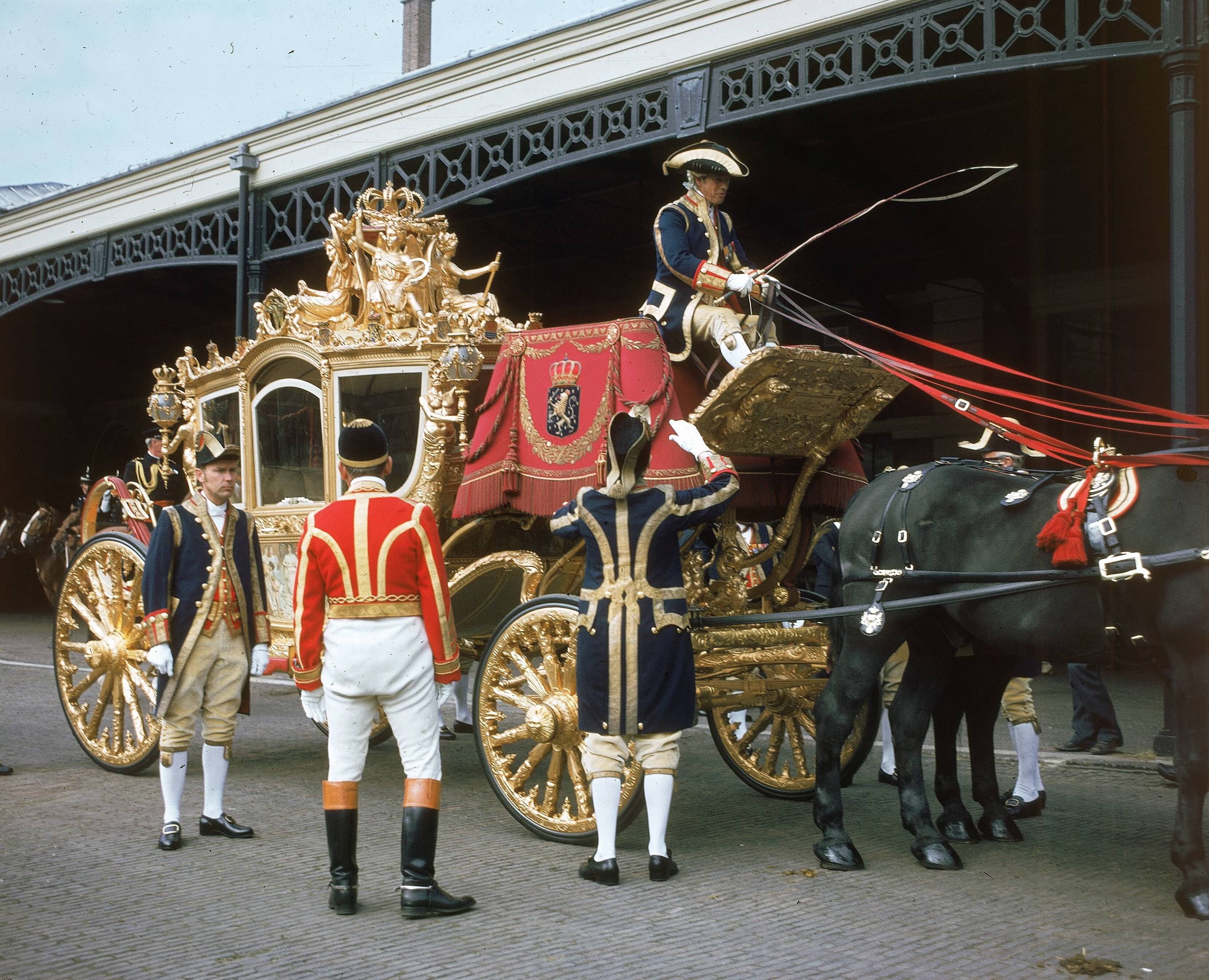 Fotocollectie RVD / Koninklijk Huis — Prinsjesdag - Gouden koets met koetsier, lakeien, stalpersoneel en paard op de binnenplaats van de koninklijke stallen aan de Noordwal in Den Haag — Foto: Mastenbroek, Cees / RVD. Licentie: Set B: Rechtenvrij / Publiek Domein. Bron: Nationaal Archief. http://hdl.handle.net/10648/afb26f94-d0b4-102d-bcf8-003048976d84