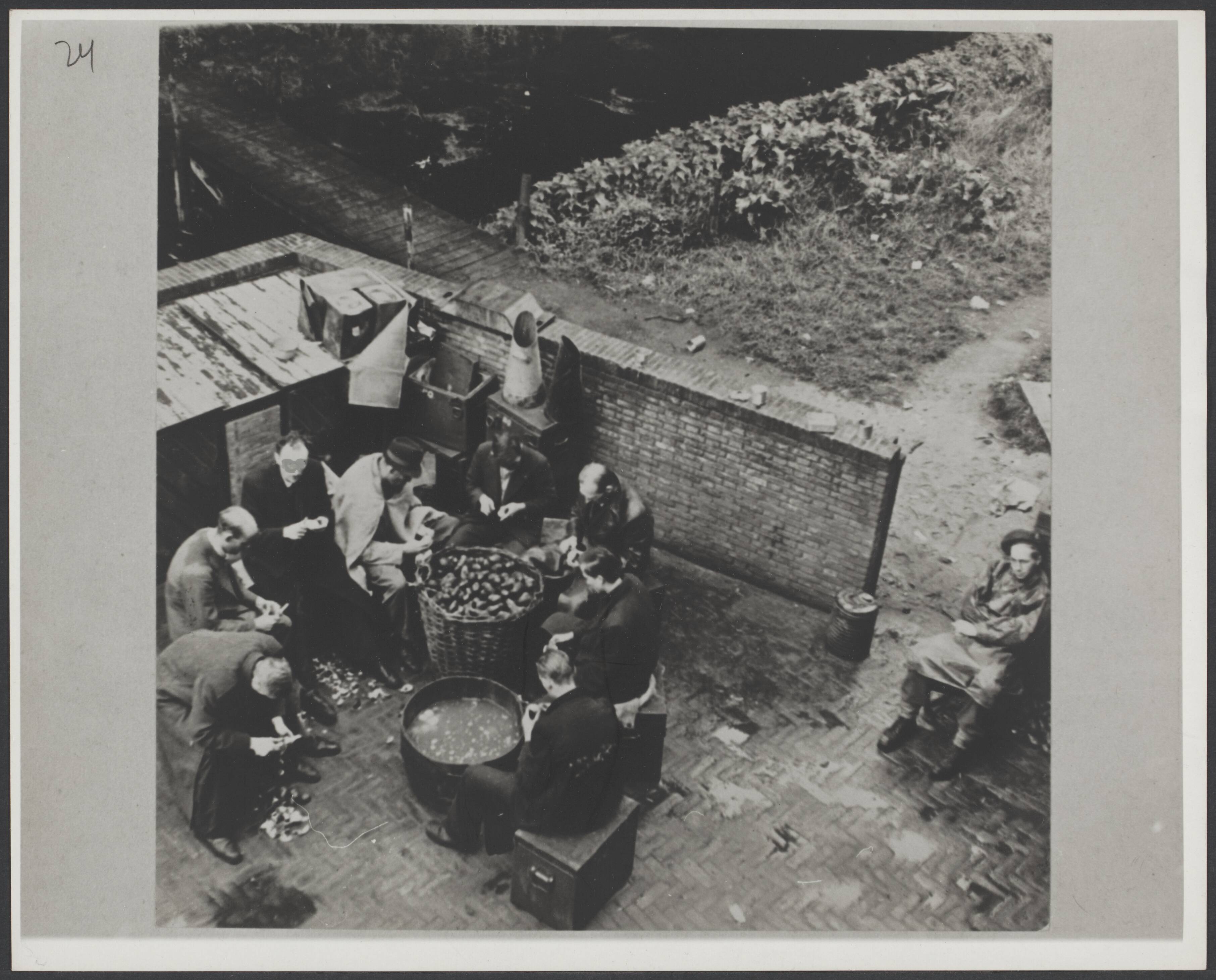 Collaboratie — Geïnterneerde NSB-ers, onder bewaking, aan het aardappels schillen te Den Haag — Foto: Jansen, H. / Anefo. Licentie: Set B: Rechtenvrij / Publiek Domein. Bron: Nationaal Archief. http://hdl.handle.net/10648/dfc1740d-2971-b324-60e5-7d85651ddf6d