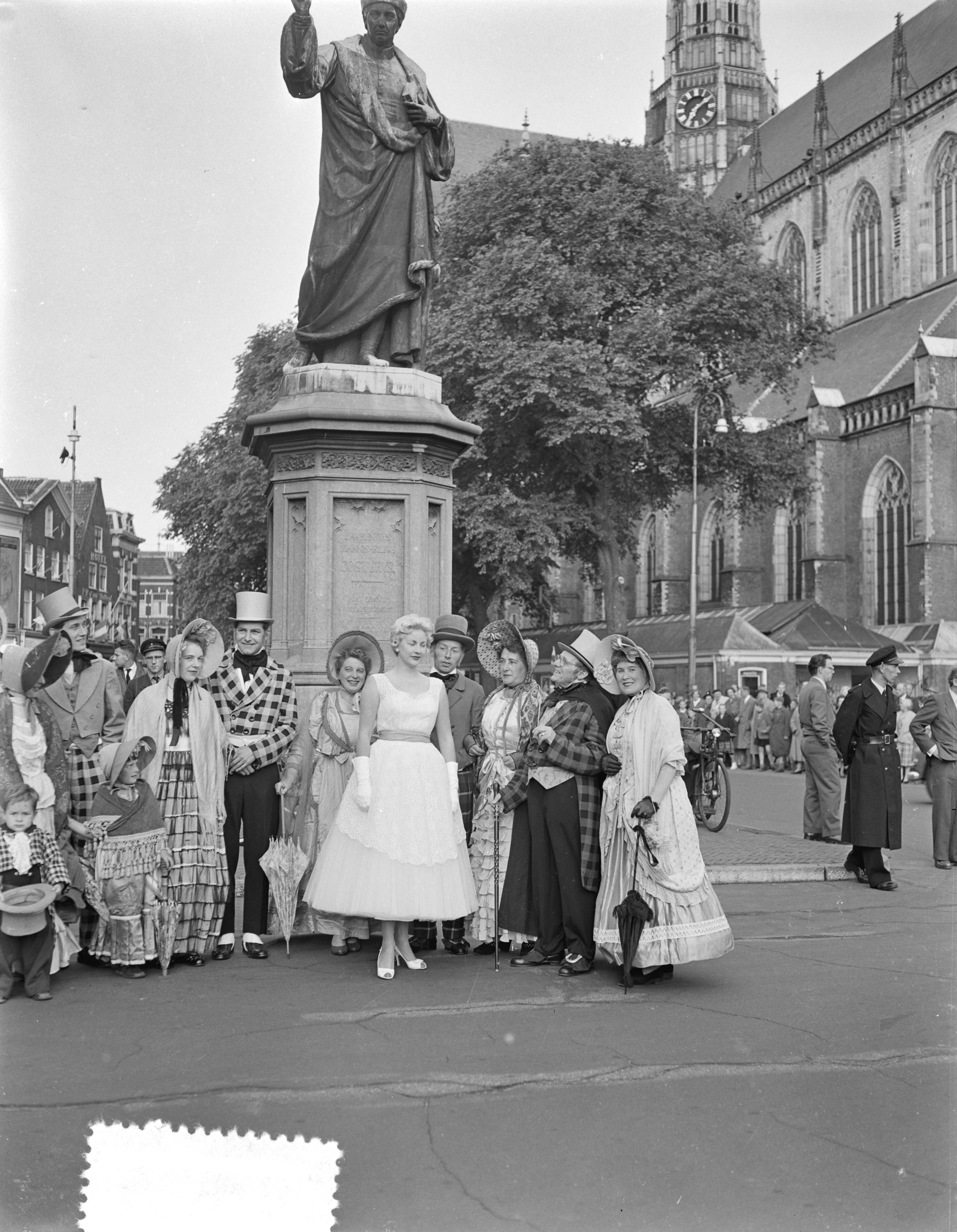 Fotocollectie Anefo — Feest seringenkoningin Haarlem. Bij haar staat een groep gekleed in historische kostuums op de Grote Markt voor het standbeeld van Laurens Jansz. Coster — Foto: Pot, Harry / Anefo. Licentie: Set B: Rechtenvrij / Publiek Domein. Bron: Nationaal Archief. http://hdl.handle.net/10648/a9498048-d0b4-102d-bcf8-003048976d84