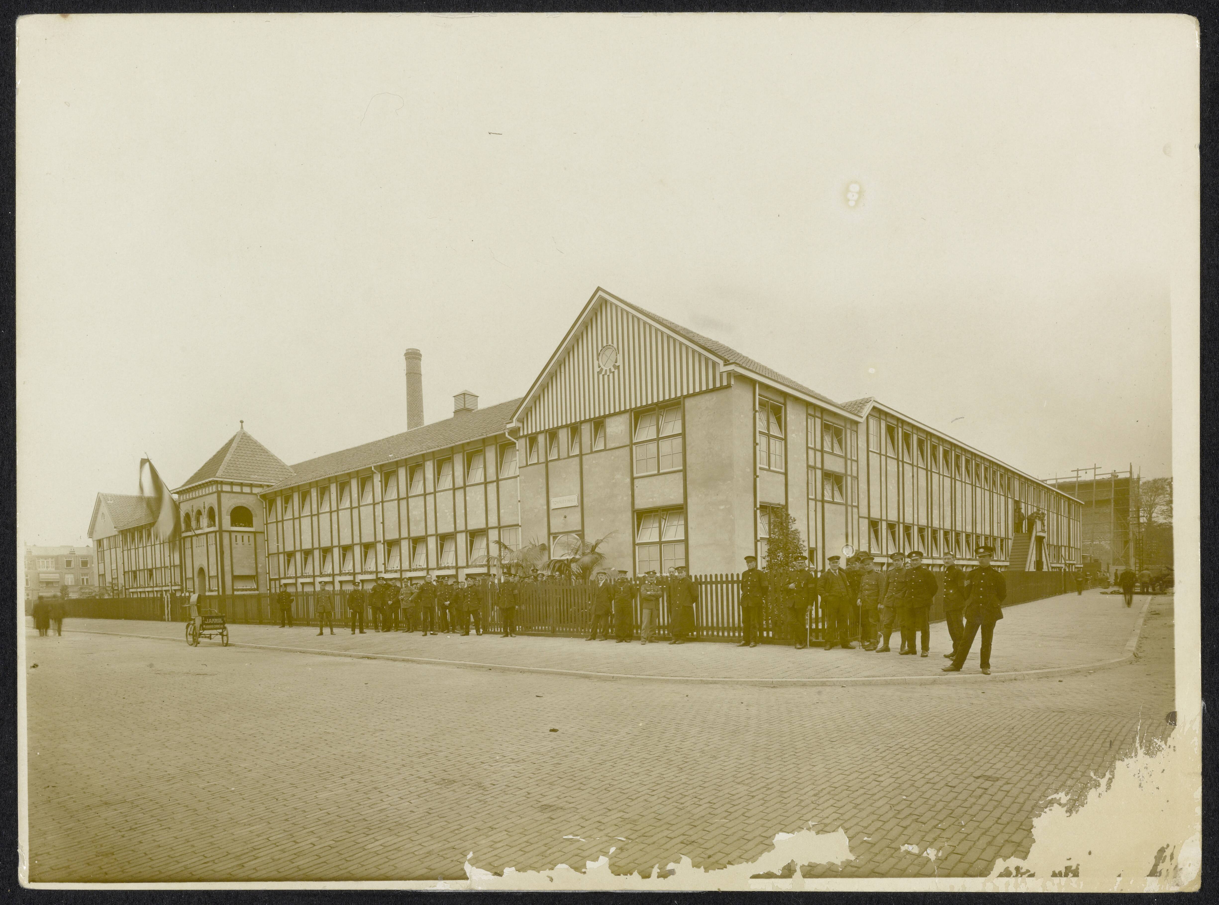 Fotocollectie Eerste Wereldoorlog — Geïnterneerde Engelse militairen voor Townley Hall in de Bachmanstraat te Den Haag. Bakfiets van J.A. Krul, Noord Einde 44. — Foto: N.V. Vereenigde Fotobureaux. Licentie: Set B: Rechtenvrij / Publiek Domein. Bron: Nationaal Archief. http://hdl.handle.net/10648/af9515b6-d0b4-102d-bcf8-003048976d84