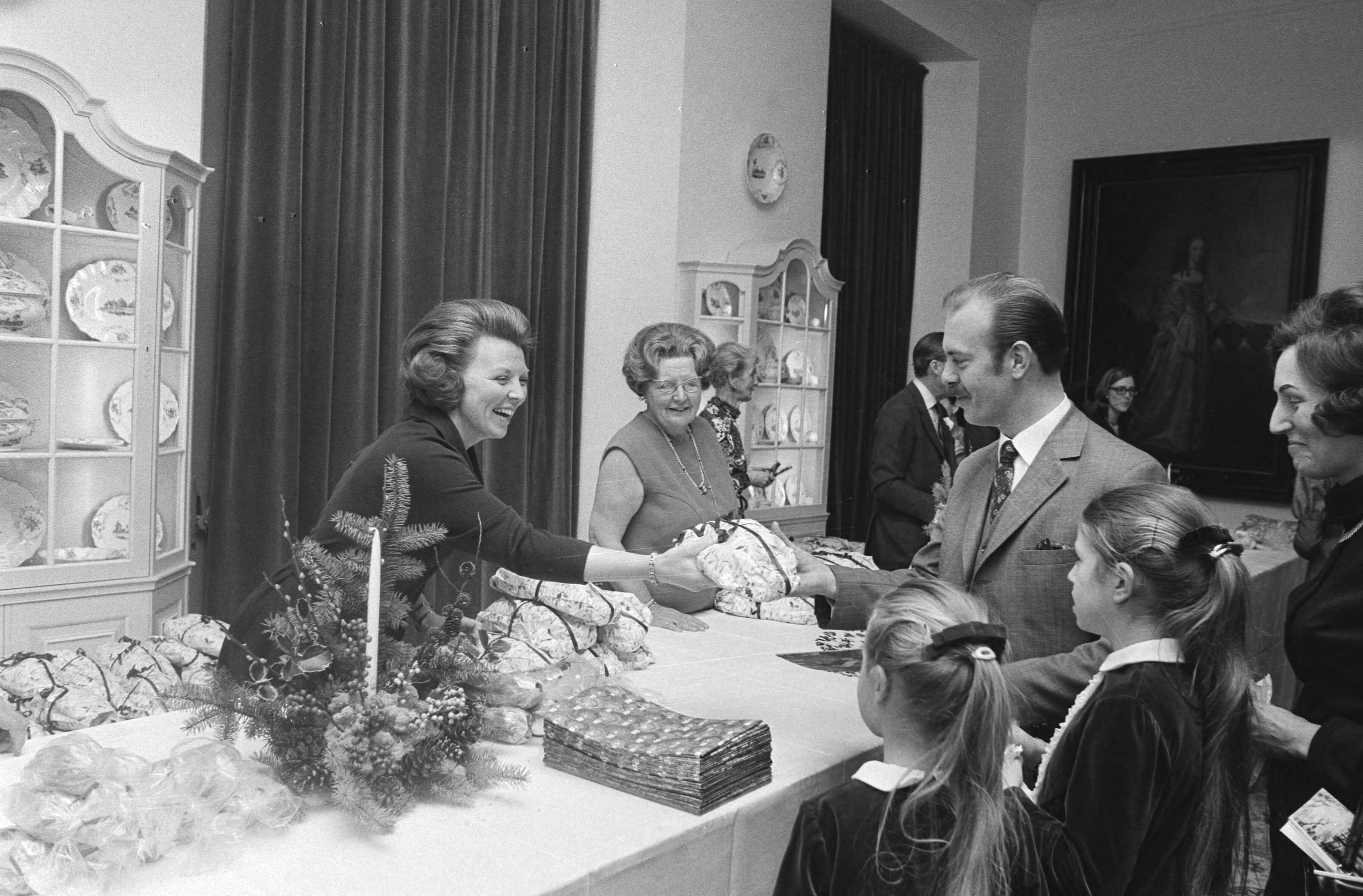 Fotocollectie Anefo — Koninklijk Huis houdt jaarlijks Kerstfeest voor personeel op Huis ten Bosch , Den Haag ; Prinses Beatrix en koningin Juliana delen brood uit / — Foto: Mieremet, Rob / Anefo. Licentie: Set B: Rechtenvrij / Publiek Domein. Bron: Nationaal Archief. http://hdl.handle.net/10648/abae29c4-d0b4-102d-bcf8-003048976d84