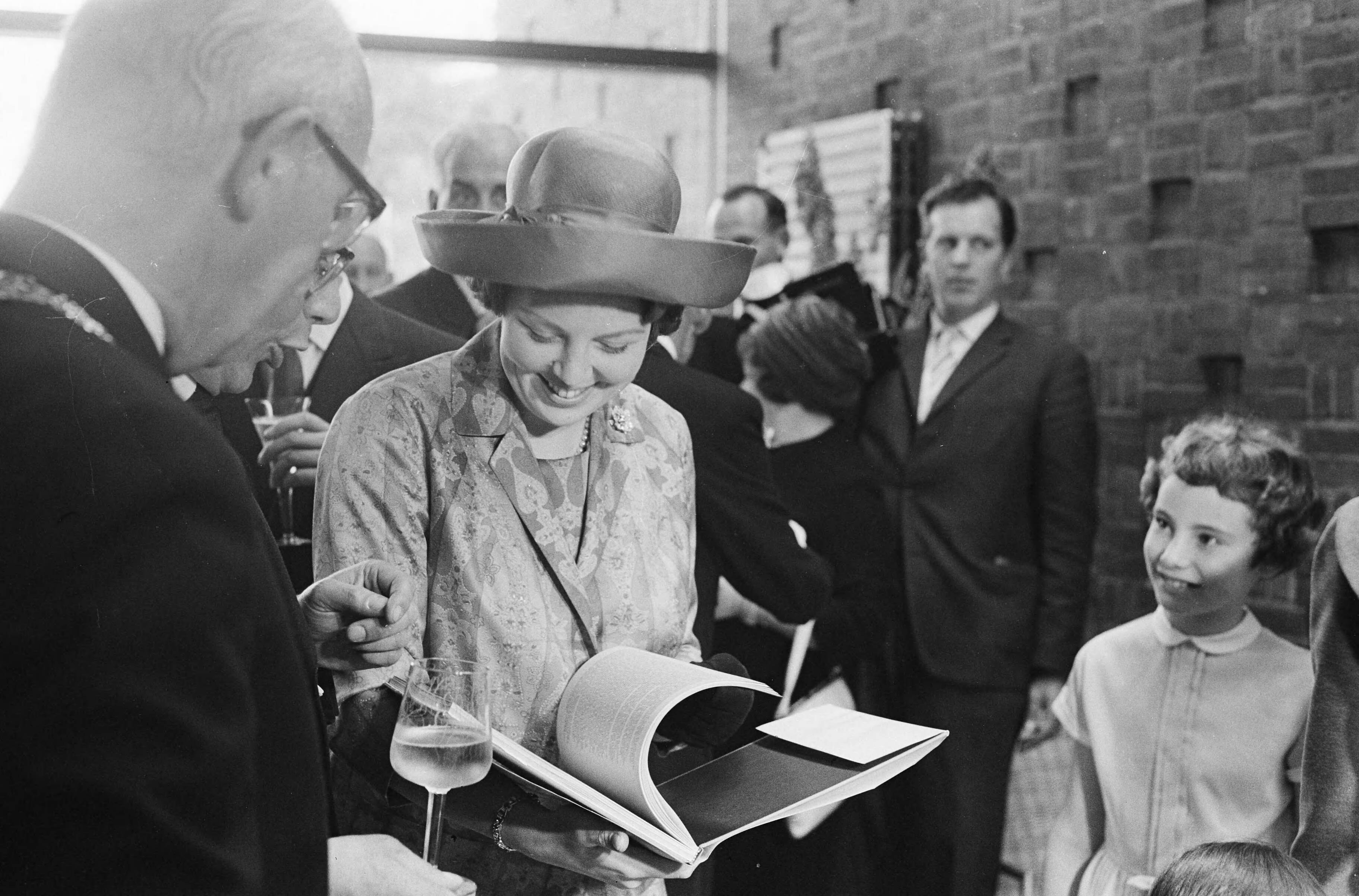 Fotocollectie Anefo — Prinses Beatrix opende nieuwe vleugel van het Haags Gemeentemuseum. De prinses bekijkt een boek. Links burgemeester Kolfschoten — Foto: Pot, Harry / Anefo. Licentie: Set B: Rechtenvrij / Publiek Domein. Bron: Nationaal Archief. http://hdl.handle.net/10648/aa0f4134-d0b4-102d-bcf8-003048976d84