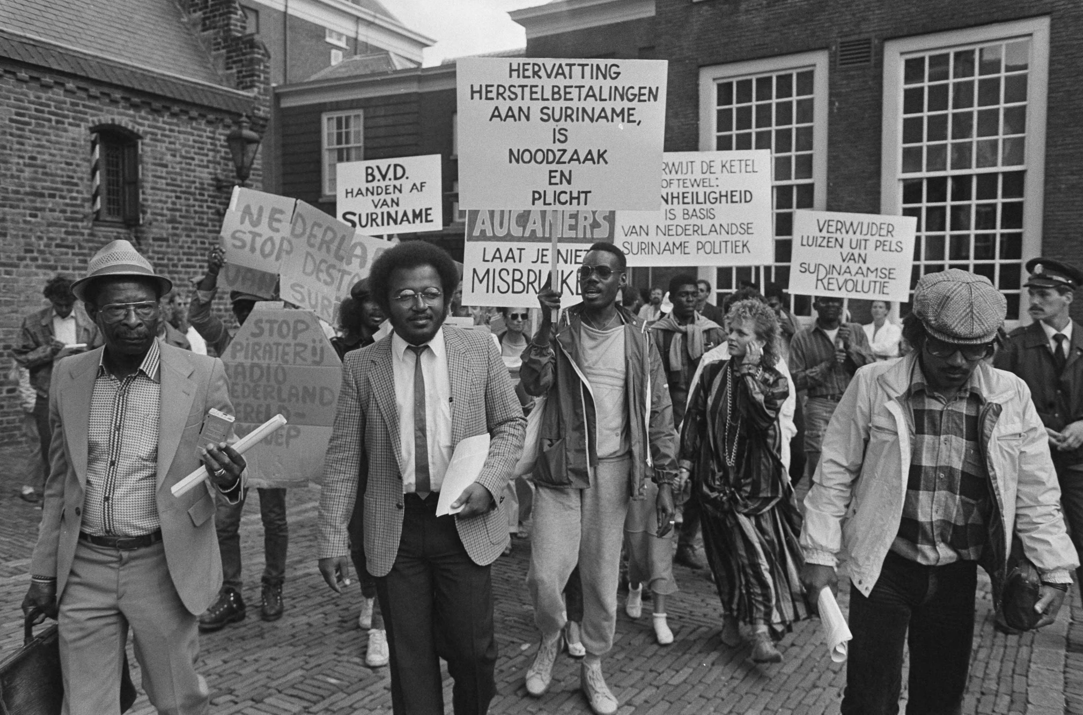 Fotocollectie Anefo — Pro Bouterse bijeenkomst in Den Haag ; remonstranten en van Mulier op Binnenhof — Foto: Croes, Rob C. / Anefo. Licentie: Set B: Rechtenvrij / Publiek Domein. Bron: Nationaal Archief. http://hdl.handle.net/10648/ad55d75e-d0b4-102d-bcf8-003048976d84