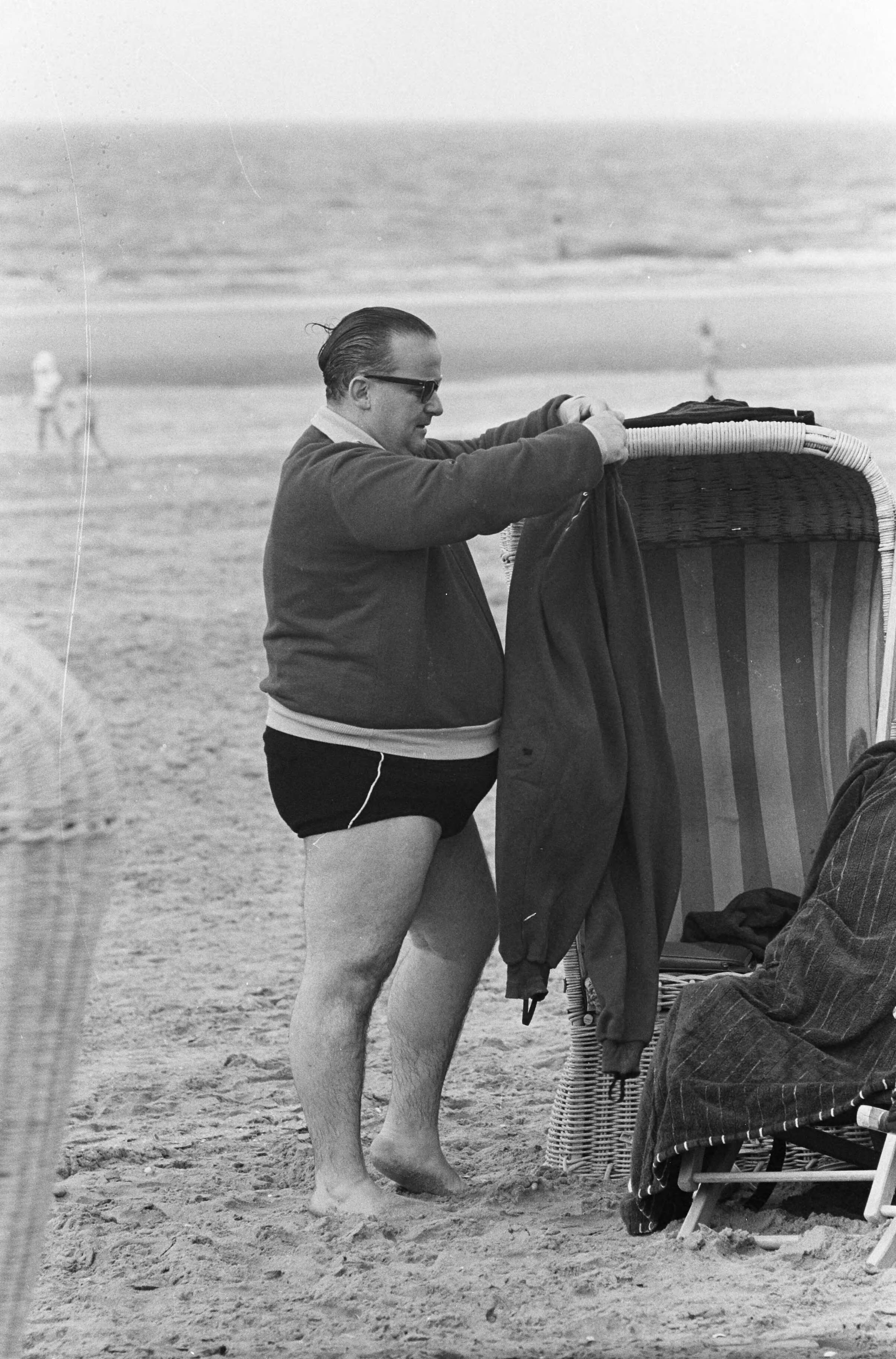 Fotocollectie Anefo — Strand Zandvoort. Corpulente heer probeert zich in broek te wurmen — Foto: Pot, Harry / Anefo. Licentie: Set B: Rechtenvrij / Publiek Domein. Bron: Nationaal Archief. http://hdl.handle.net/10648/aa0b692e-d0b4-102d-bcf8-003048976d84