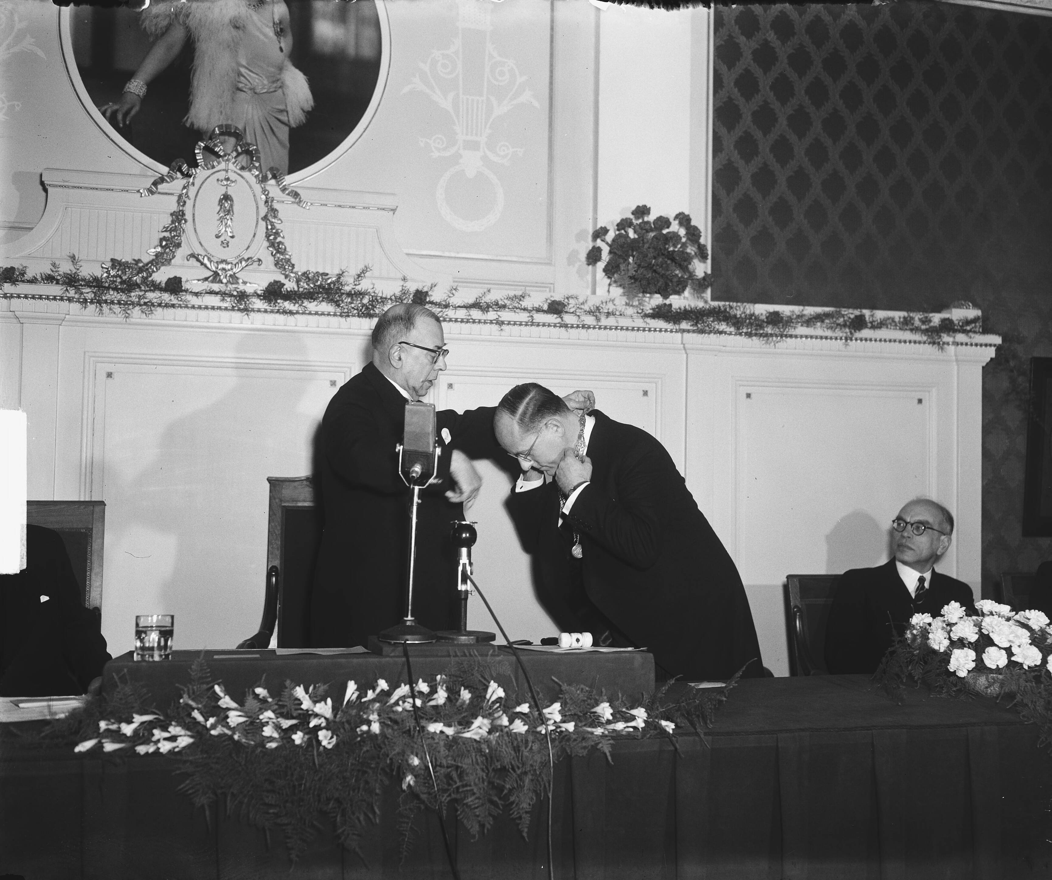 Fotocollectie Anefo — Installatie nieuwe burgemeester van Den Haag, F.M.A. Schokking, door loco-burgemeester en wethouder Dr. L.J.M. Feber. Feber hangt Schokking de ambtsketen om — Foto: Winterbergen, Rolf / Anefo. Licentie: Set B: Rechtenvrij / Publiek Domein. Bron: Nationaal Archief. http://hdl.handle.net/10648/a8d1f9b0-d0b4-102d-bcf8-003048976d84