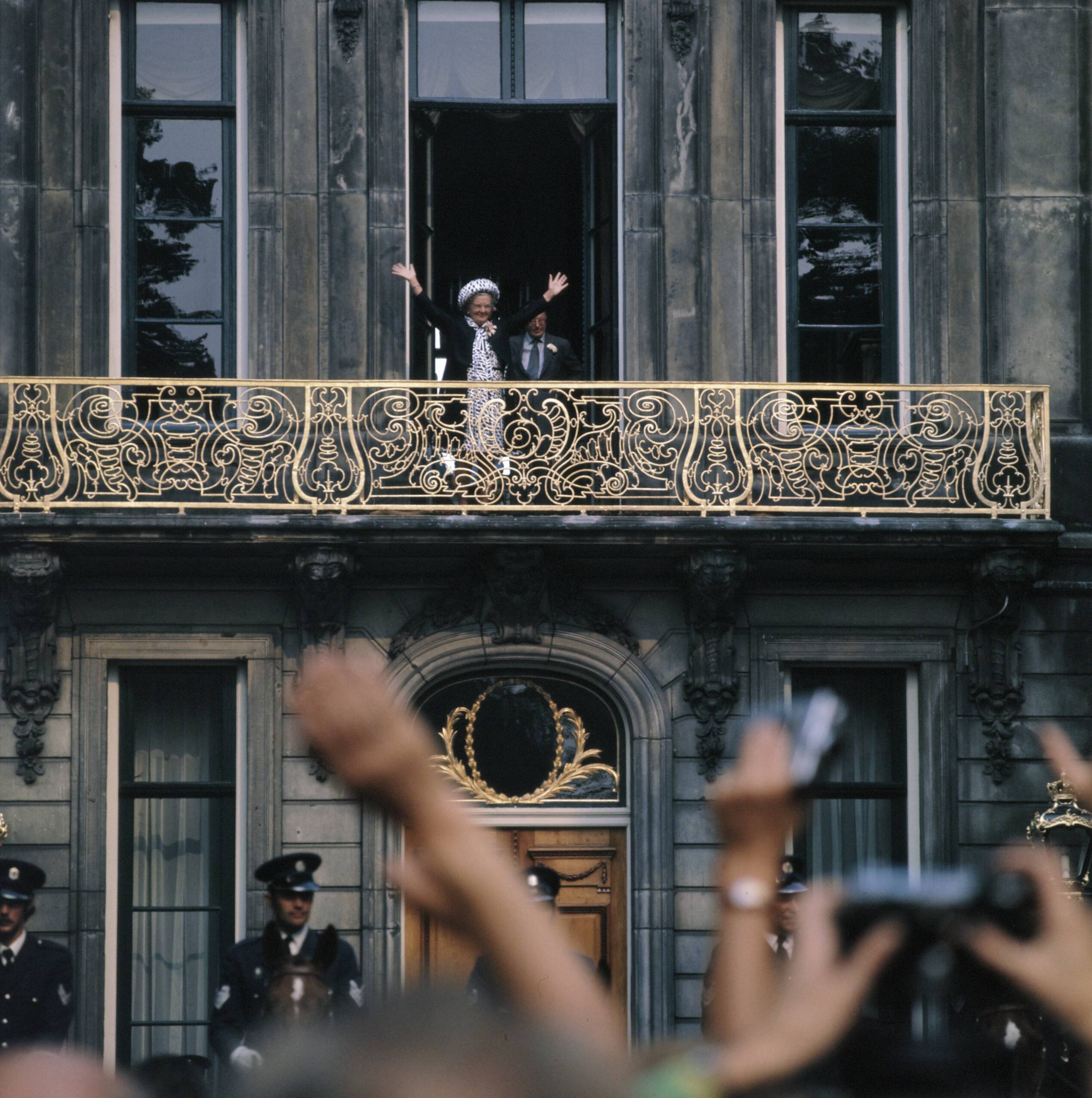 Fotocollectie Anefo — Koninklijke familie bij viering Regeringsjubileum in Den Haag; koningin Juliana met beide handen zwaaiend op het balkon — Foto: Mieremet, Rob / Anefo. Licentie: Set B: Rechtenvrij / Publiek Domein. Bron: Nationaal Archief. http://hdl.handle.net/10648/ad929ca2-d0b4-102d-bcf8-003048976d84