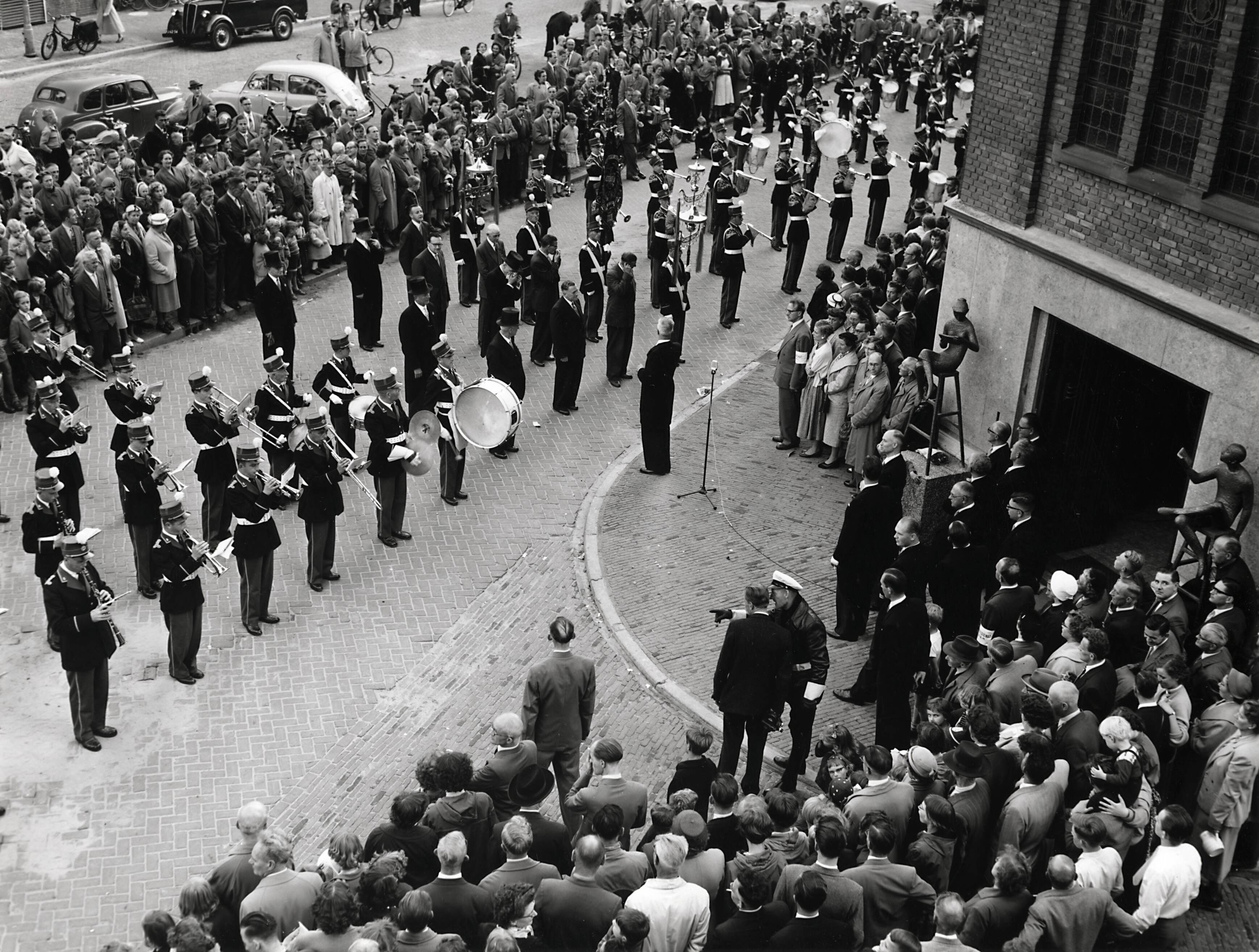 Collectie nader te bepalen — [50-jarig jubileum N.V. De Spaarnestad] [onthulling van de beelden van Hans Petri bij de hoofdingang van het Spaarnestadgebouw aan de Nassaulaan te Haarlem] [een muziekkorps speelt] — Foto: Fotograaf Onbekend / Fotobureau onbekend / Spaarnestad Photo (05887). Licentie: Set B: Rechtenvrij / Publiek Domein. Bron: Nationaal Archief. http://hdl.handle.net/10648/35429da6-3a92-a382-e063-6df0900a6686