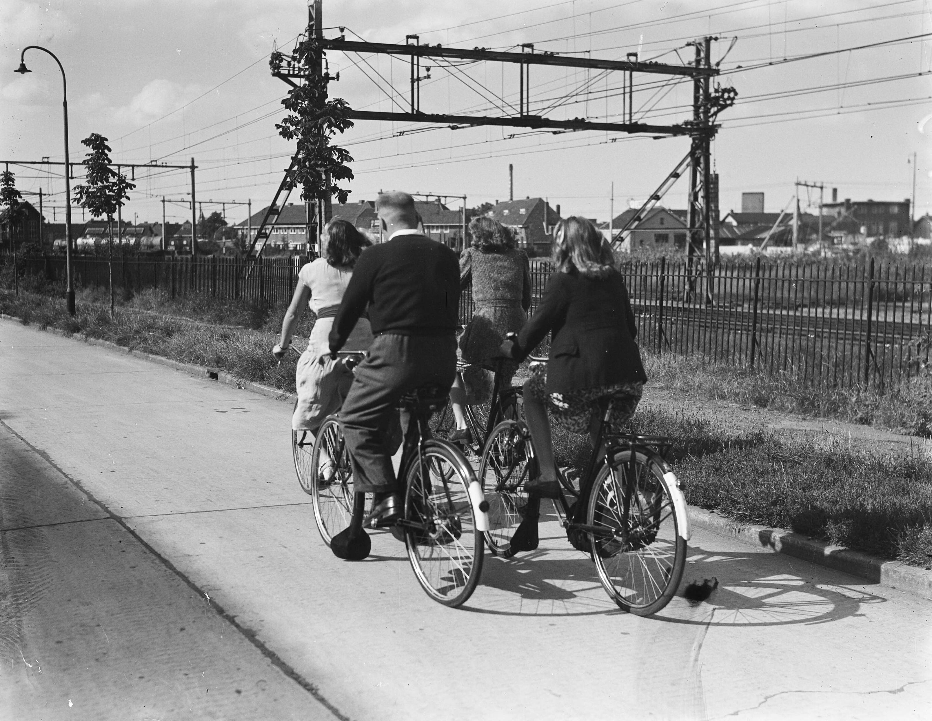 Zwemtrainer Jan Stender met zwemsters — Stender en zijn zwemsters op de fiets [rijden langs een spoorbaan] — Foto: Noske, J.D. / Anefo. Licentie: Set B: Rechtenvrij / Publiek Domein. Bron: Nationaal Archief. http://hdl.handle.net/10648/a8ba2a74-d0b4-102d-bcf8-003048976d84