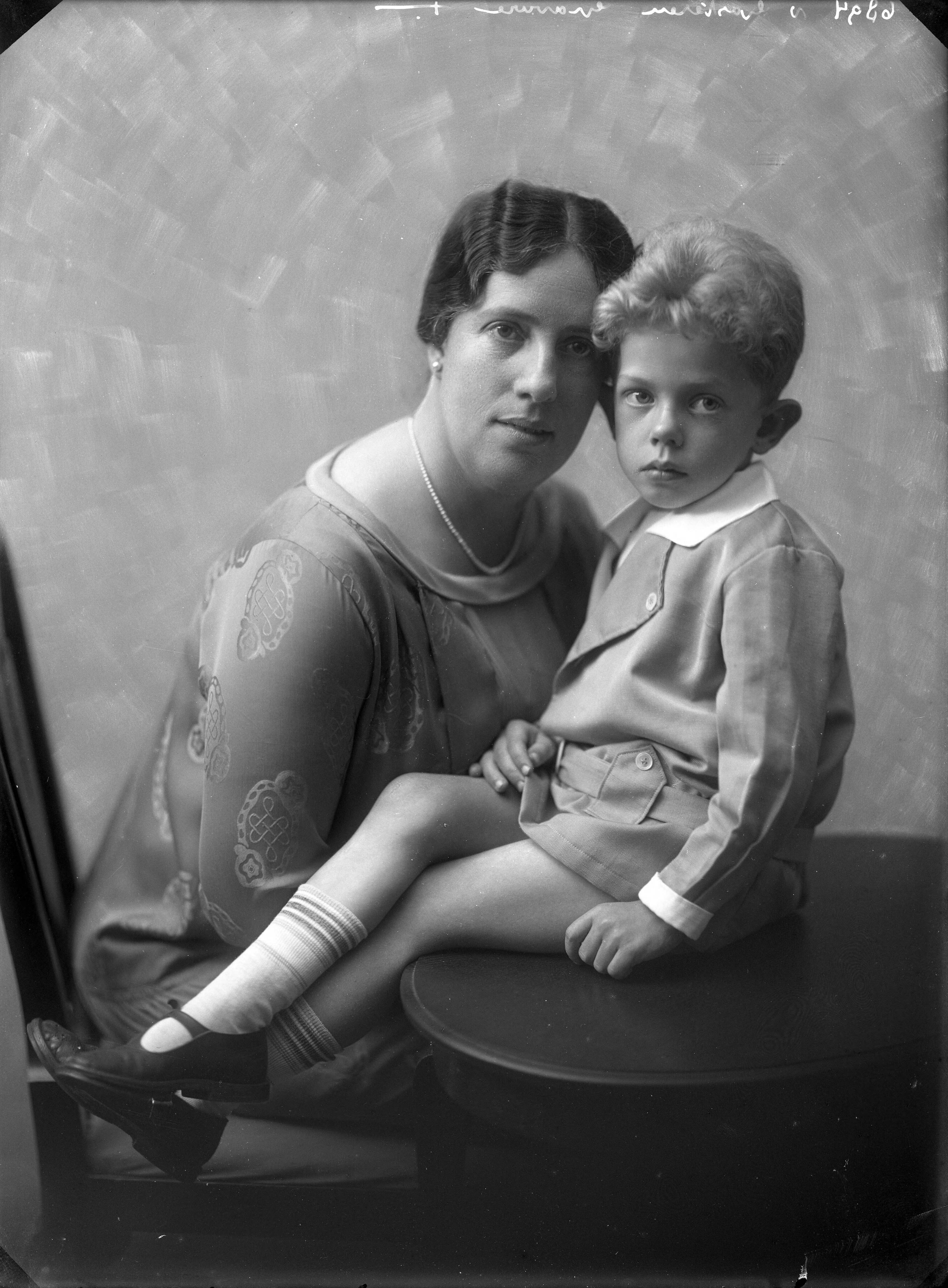 Berg, van den (BERG 050) — Studio-opnames. Moeder en zoontje in de studio, het jongetje zit op de tafel, waar de moeder ook tegen aanleunt. Haarlem, Nederland. 1918-1930. 6894 v. Gasteren gravure — Foto: Berg, Th.C.J. van den / Spaarnestad Photo (05887). Licentie: Set B: Rechtenvrij / Publiek Domein. Bron: Nationaal Archief. http://hdl.handle.net/10648/35429da7-c710-a382-e063-6df0900a6686