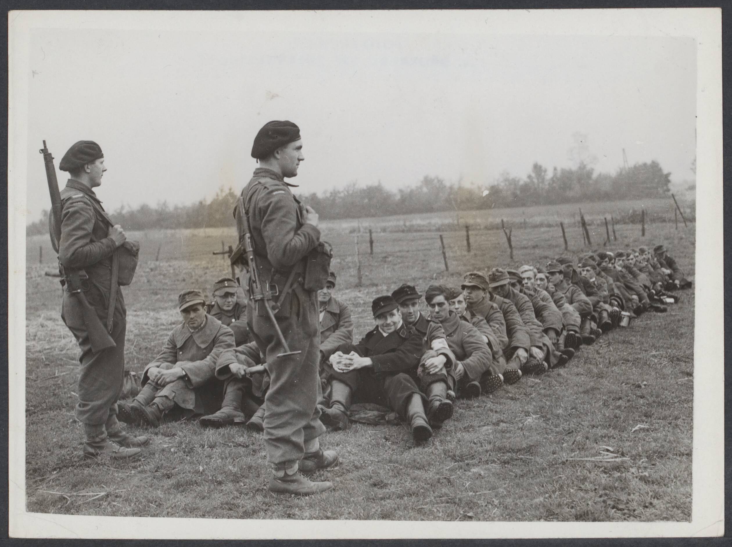 Nederland front, 1944 — Poolse leger aan het front Breda-Tilburg. Na de verovering van Alphen en Gilze. Poolse bewakers en Duitse krijgsgevangen die dicht op elkaar zitten om ontsnapping te voorkomen — Foto: Keystone / Rechtenvrij. Licentie: Set B: Rechtenvrij / Publiek Domein. Bron: Nationaal Archief. http://hdl.handle.net/10648/ee9dd582-f097-cc9f-7273-c953f111e58d