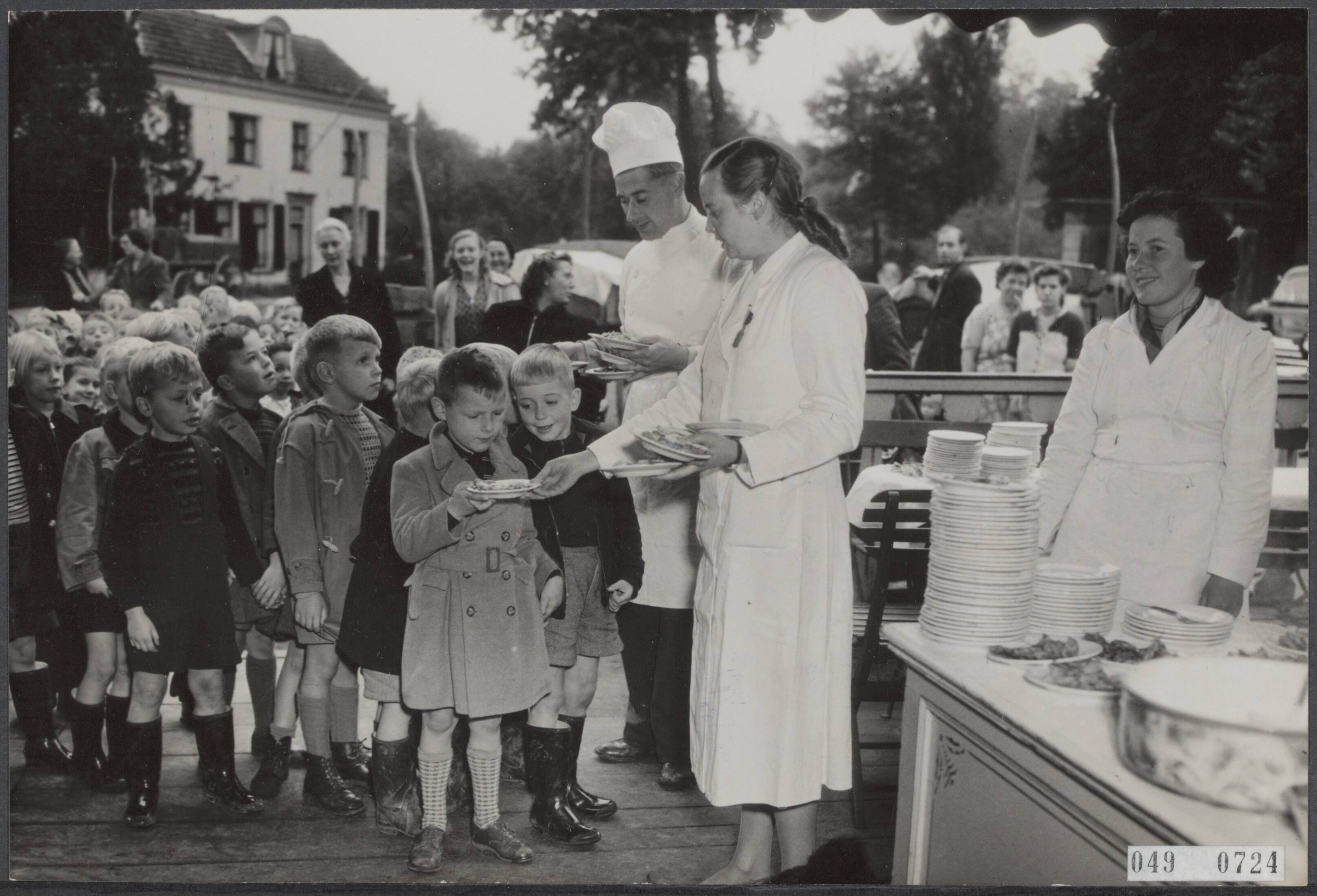 Fotocollectie Elsevier Binnenland — Kinderen uit Breukelen krijgen poffertjes op de jaardag van Willem Corneille Dudok van Wit (1843-1913), alias Kees de Tippelaar. Het was de 39ste keer nadat het testament van wijlen Dudok de Vwit werd geopend waarin hij een fonds stichtte waaruit ieder jaar de schooljeugd van Breukelen op poffertjes wordt getracteerd — Foto: Fotograaf Onbekend / Anefo. Licentie: Set B: Rechtenvrij / Publiek Domein. Bron: Nationaal Archief. http://hdl.handle.net/10648/ae01fe9e-d0b4-102d-bcf8-003048976d84