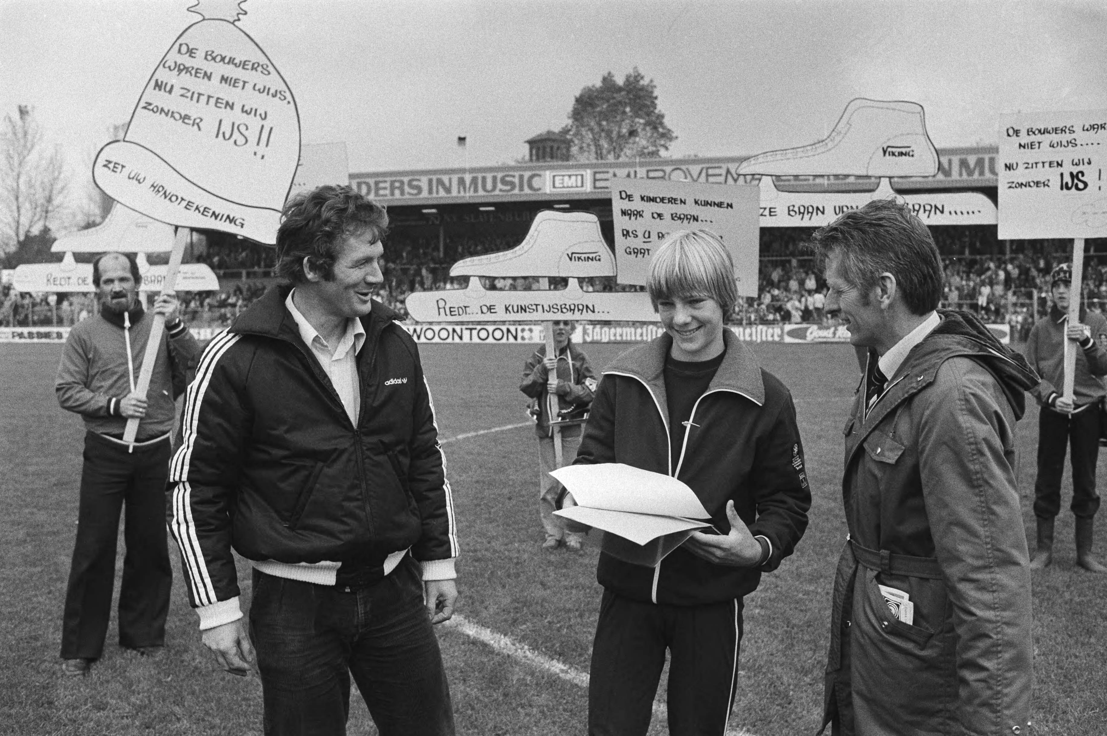 Haarlem - Ajax 2-4 (KNVB beker) — Bij deze wedstrijd werden er handtekeningen verzameld om sluiting van de kunstijsbaan tegen te gaan. In de rust zetten de schaatsers Hans van Helden en Jeen van den Berg hun handtekening — Foto: Suyk, Koen / Anefo. Licentie: Set B: Rechtenvrij / Publiek Domein. Bron: Nationaal Archief. http://hdl.handle.net/10648/acd2d606-d0b4-102d-bcf8-003048976d84