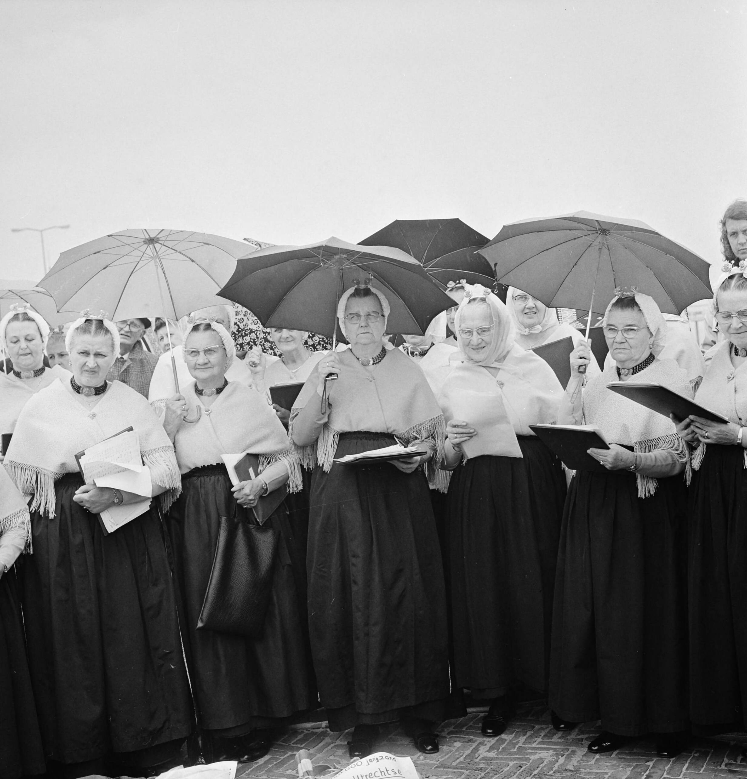 Fotocollectie Anefo — VVV-directeuren brengen zak zand naar jubilerende VVV in Scheveningen; zingende Scheveningse vrouwen in klederdracht — Foto: Mieremet, Rob / Anefo. Licentie: Set B: Rechtenvrij / Publiek Domein. Bron: Nationaal Archief. http://hdl.handle.net/10648/ac4ae2be-d0b4-102d-bcf8-003048976d84