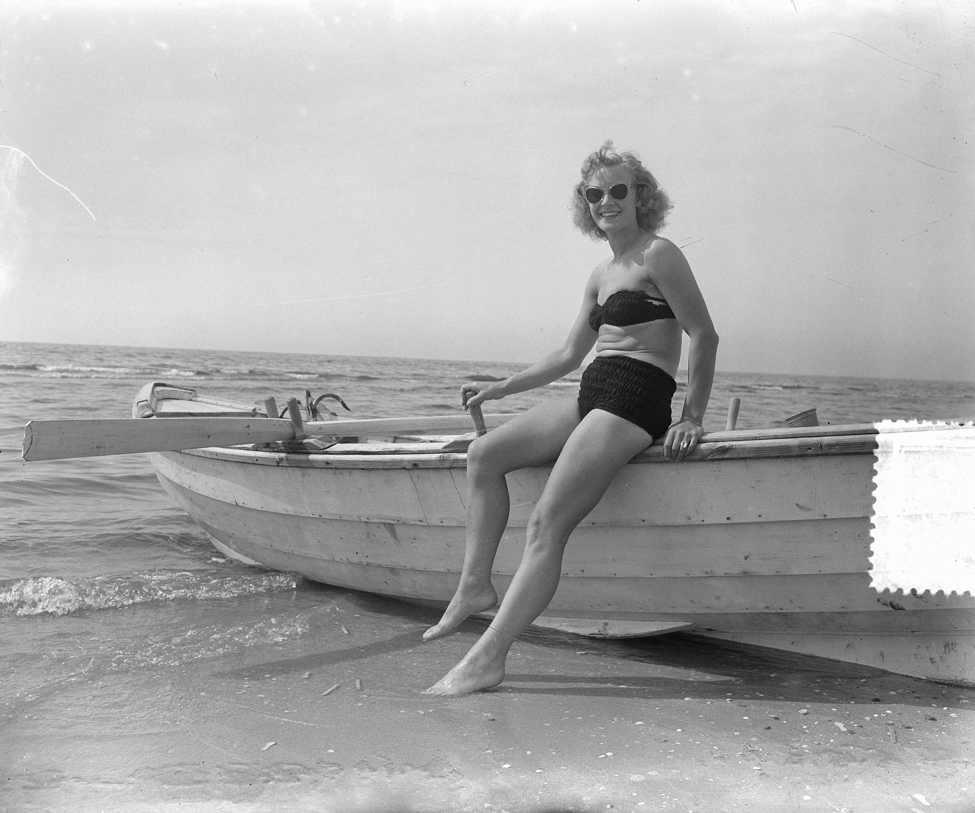 Fotocollectie Anefo — Zomerplaatjes aan strand van Zandvoort. Moeder poseert alleen bij roeiboot — Foto: Pot, Harry / Anefo. Licentie: Set B: Rechtenvrij / Publiek Domein. Bron: Nationaal Archief. http://hdl.handle.net/10648/a90e5a2c-d0b4-102d-bcf8-003048976d84