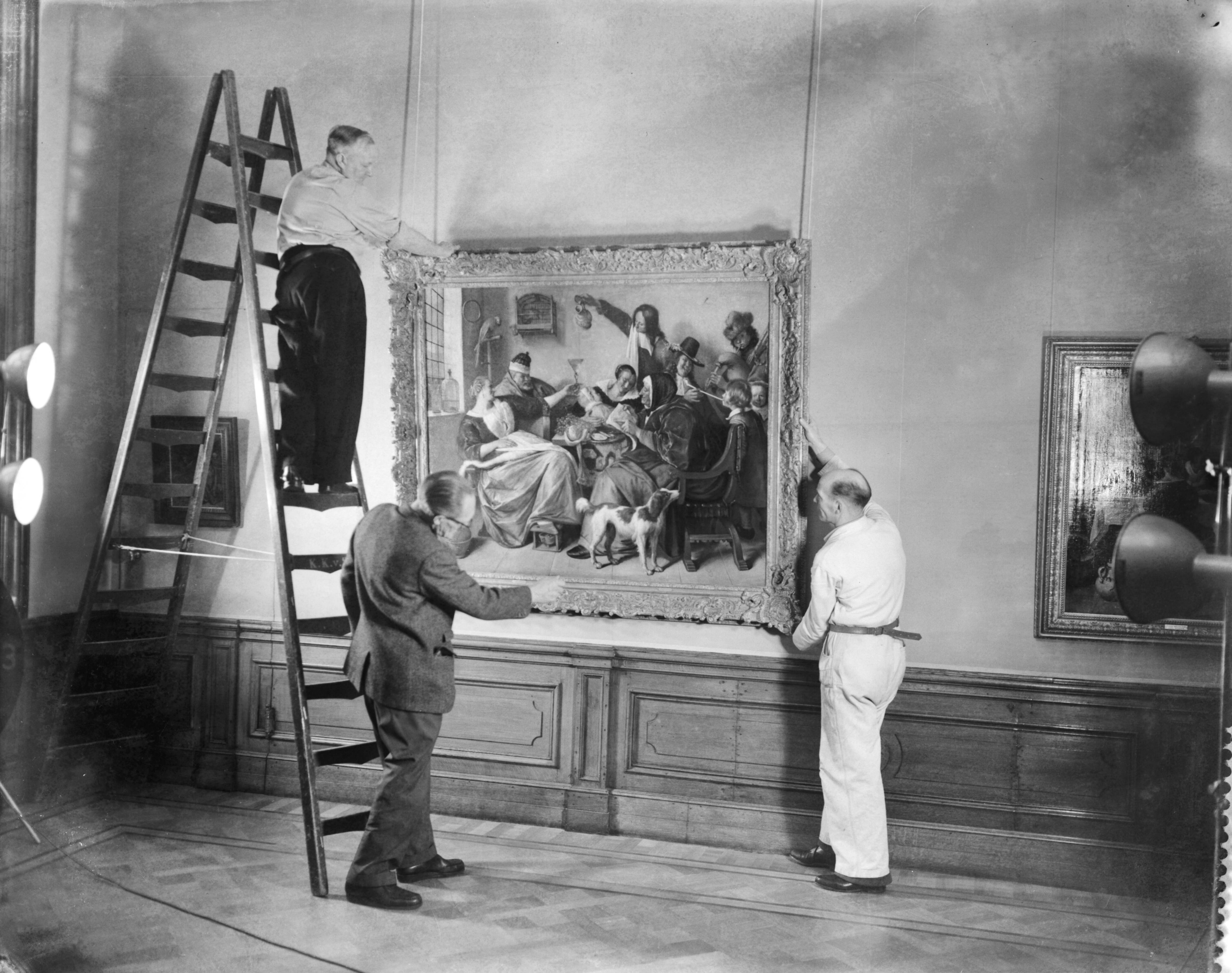 Fotocollectie Anefo — Voorbereidingen voor Jan Steen tentoonstelling in het Mauritshuis te Den Haag. Ophangen van het schilderij "Soo voer gesongen, soo na gepepen" — Foto: Behrens, Herbert F. / Anefo. Licentie: Set B: Rechtenvrij / Publiek Domein. Bron: Nationaal Archief. http://hdl.handle.net/10648/a98a6568-d0b4-102d-bcf8-003048976d84