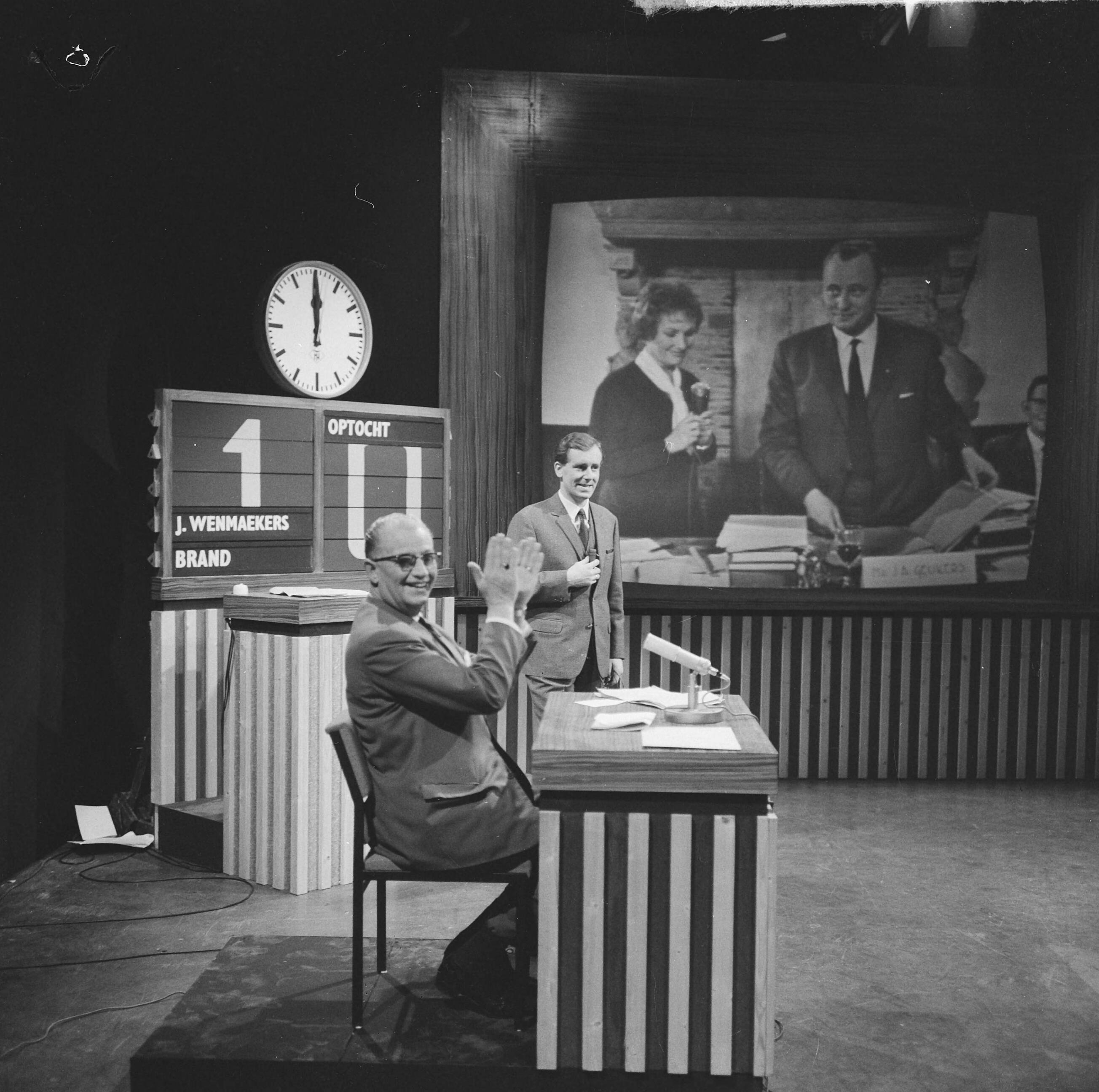Fotocollectie Anefo — NCRV-quiz 'Een tegen allen' tussen Zierikzee en Bolsward, In de studio te Bussum, achter de desk de opdrachtengever, de heer Doeleman uit Zierikzee, daarachter spelleider Dick van Ruler, op het televisiescherm presentatrice Tanja Koen en burgemeester van Bolsward, J.A. Geukers in het stadhuis van Bolsward — Foto: Nijs, Jac. de / Anefo. Licentie: Set B: Rechtenvrij / Publiek Domein. Bron: Nationaal Archief. http://hdl.handle.net/10648/aa7f3606-d0b4-102d-bcf8-003048976d84