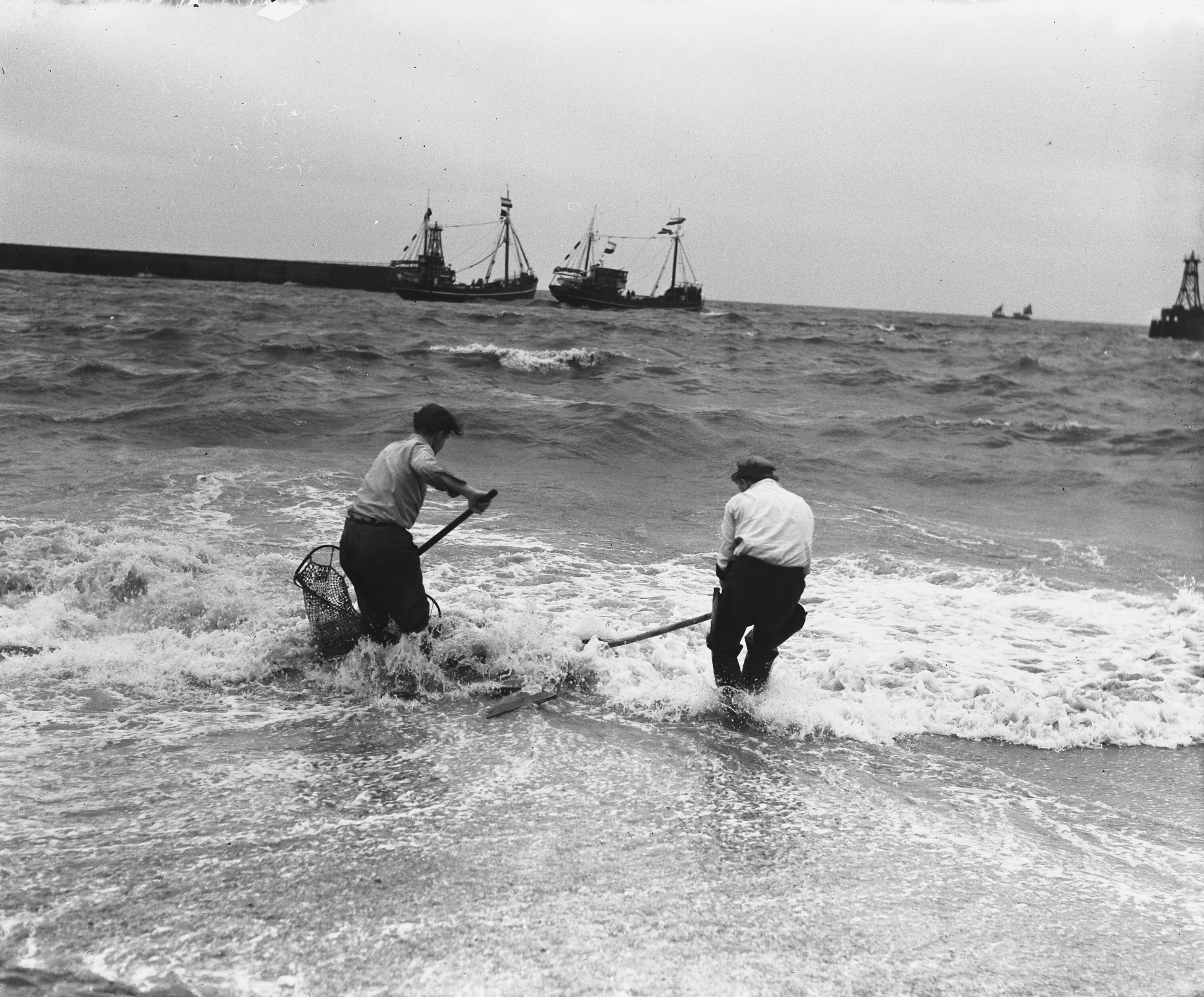 Uitvaren van de haringvloot in Scheveningen — Garnalenvissers op strand, in de achtergrond de haringvloot — Foto: Koch, Eric / Anefo. Licentie: Set B: Rechtenvrij / Publiek Domein. Bron: Nationaal Archief. http://hdl.handle.net/10648/a97c47ee-d0b4-102d-bcf8-003048976d84