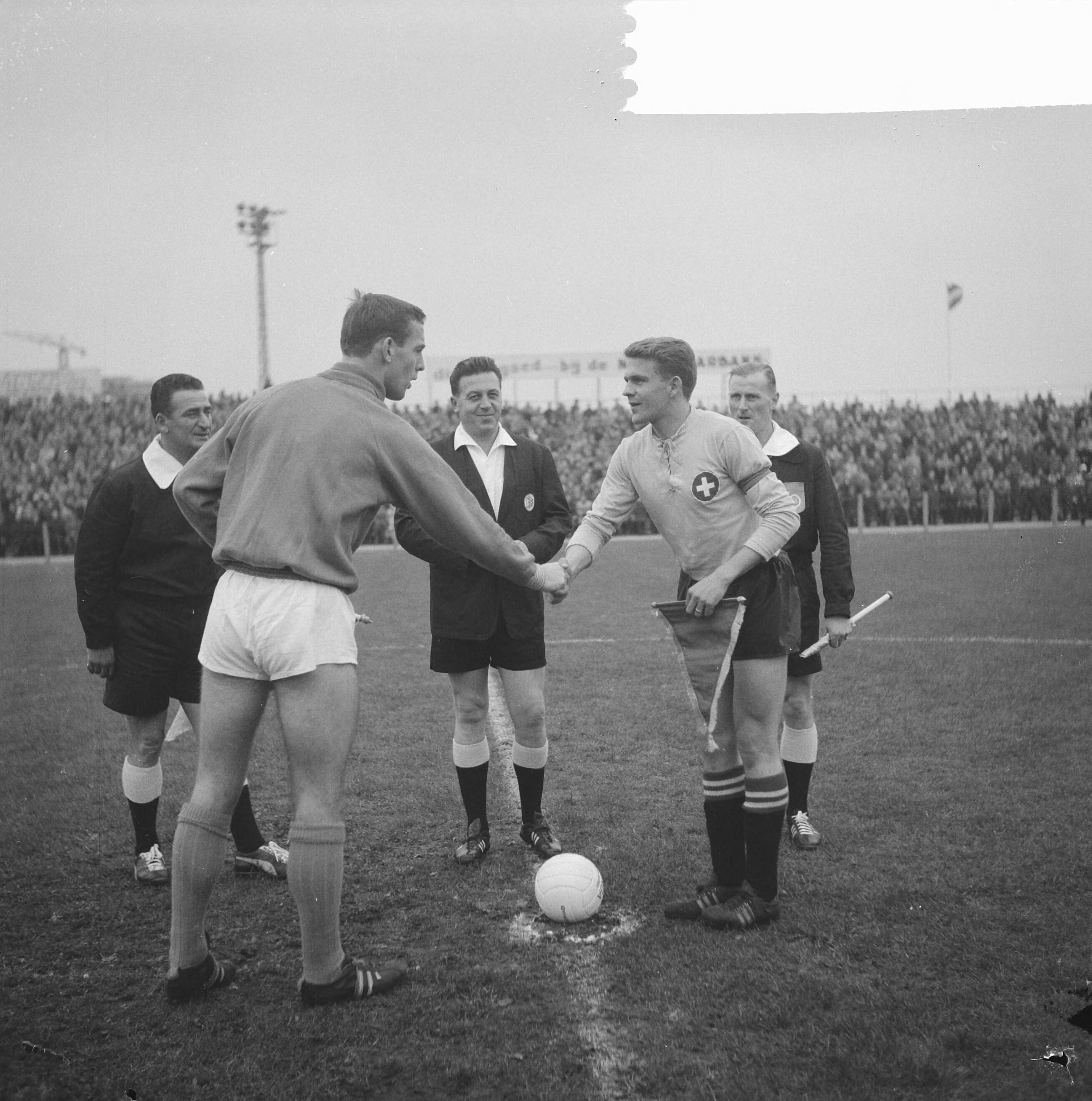Fotocollectie Anefo — Voetbal. Jong Oranje tegen Jong Zwitserland 4-1. De toss, links aanvoerder Gerrit Borghuis — Foto: Nijs, Jac. de / Anefo. Licentie: Set B: Rechtenvrij / Publiek Domein. Bron: Nationaal Archief. http://hdl.handle.net/10648/aa1ebe20-d0b4-102d-bcf8-003048976d84