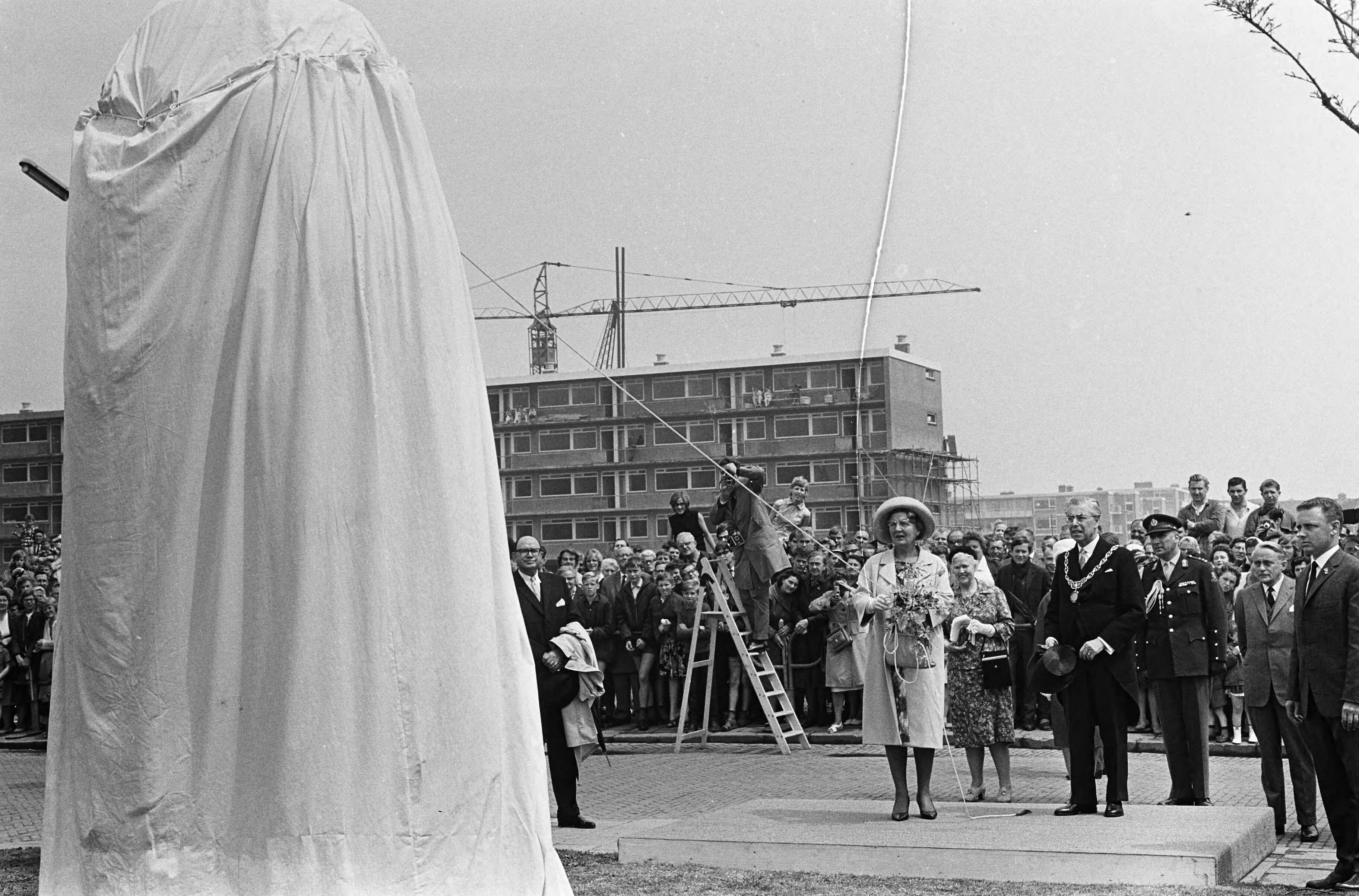 Koningin Juliana brengt een bezoek aan Gouda en Rotterdam — Koningin onthult bronzen beeld 'De Ontheemden' ('Displaced Persons') van beeldhouwer Albert Stewart. Naast haar K.F.O. James, de burgemeester van Gouda — Foto: Fotograaf Onbekend / Anefo. Licentie: Set B: Rechtenvrij / Publiek Domein. Bron: Nationaal Archief. http://hdl.handle.net/10648/aa6d7b28-d0b4-102d-bcf8-003048976d84