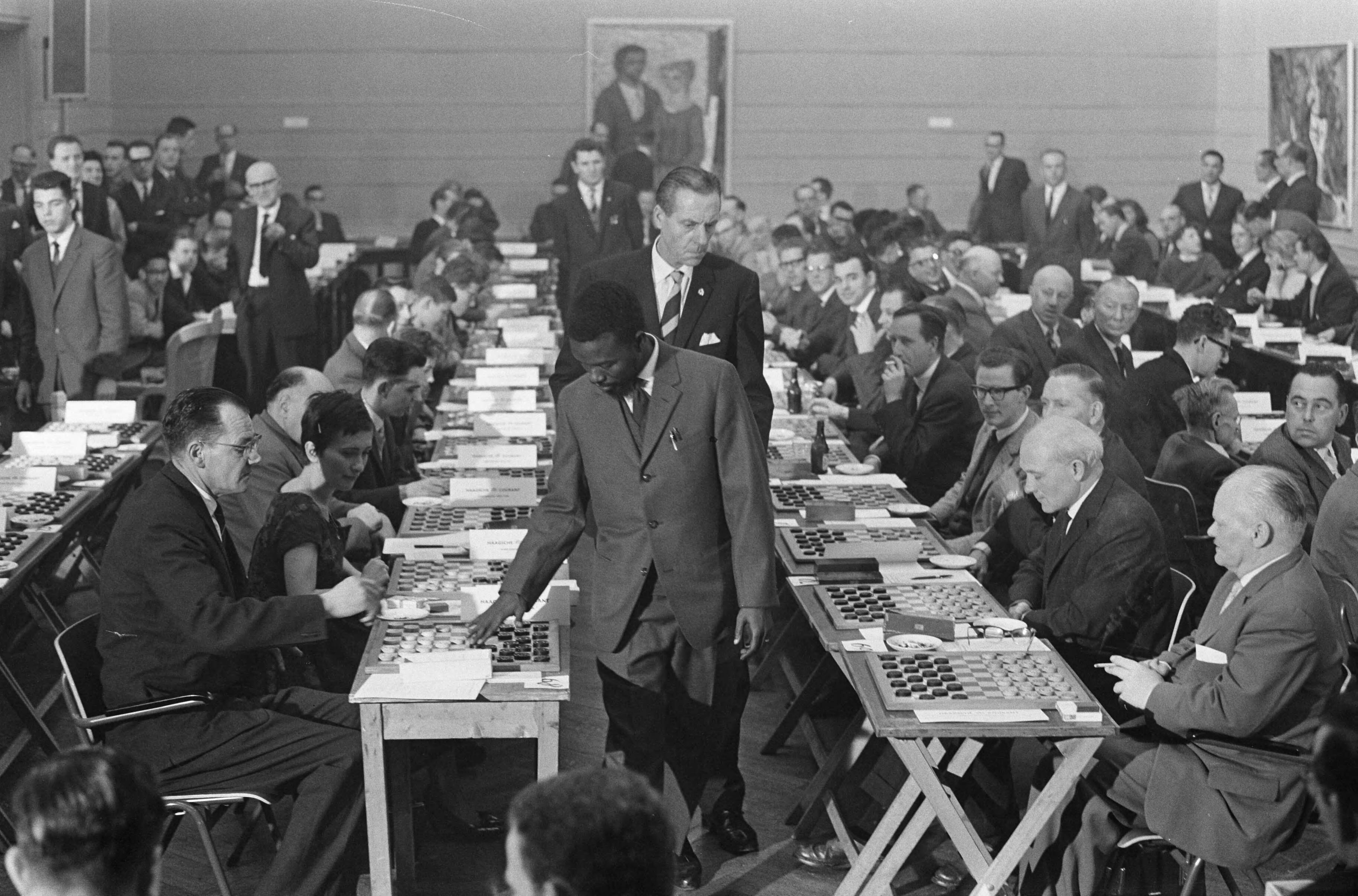 Fotocollectie Anefo — Wereldrecord simultaandammen van Baba Sy in Den Haag . Baba Sy tijdens de simultaanseance — Foto: Rossem, Wim van / Anefo. Licentie: Set B: Rechtenvrij / Publiek Domein. Bron: Nationaal Archief. http://hdl.handle.net/10648/a9f63c02-d0b4-102d-bcf8-003048976d84
