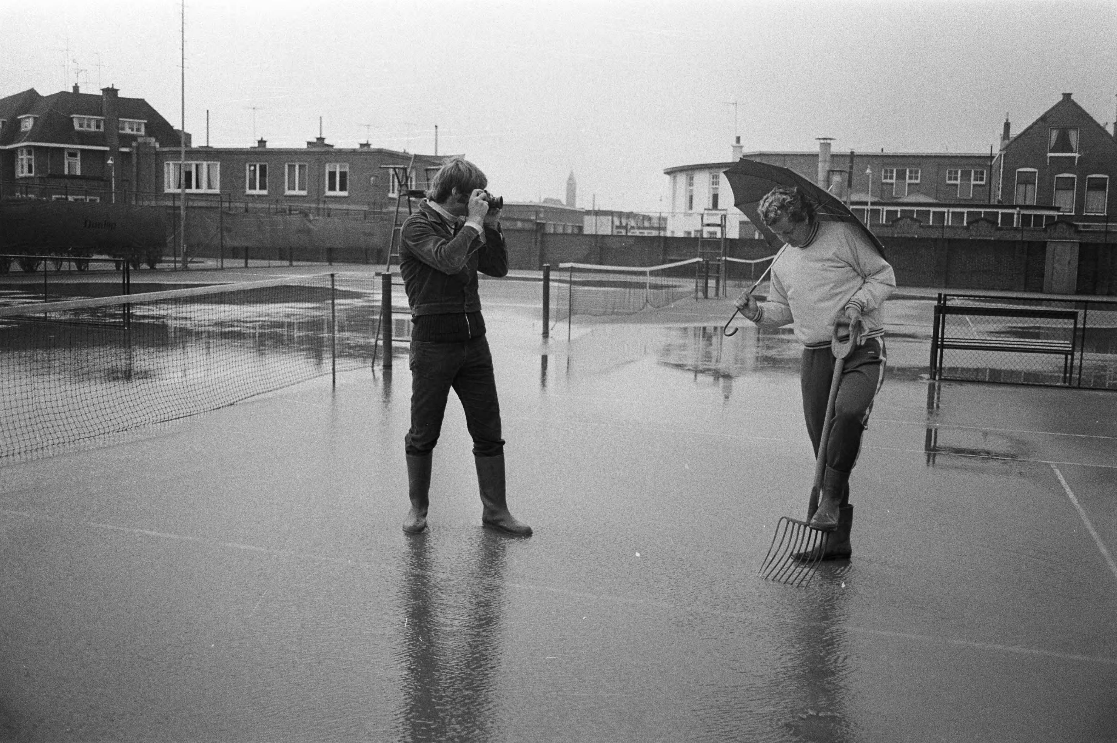 Fotocollectie Anefo — Nederlandse tenniskampioenschappen Scheveningen, regen Betty Stove prikt in baan, Fred Hemmes neemt foto — Foto: Peters, Hans / Anefo. Licentie: Set B: Rechtenvrij / Publiek Domein. Bron: Nationaal Archief. http://hdl.handle.net/10648/abc99678-d0b4-102d-bcf8-003048976d84