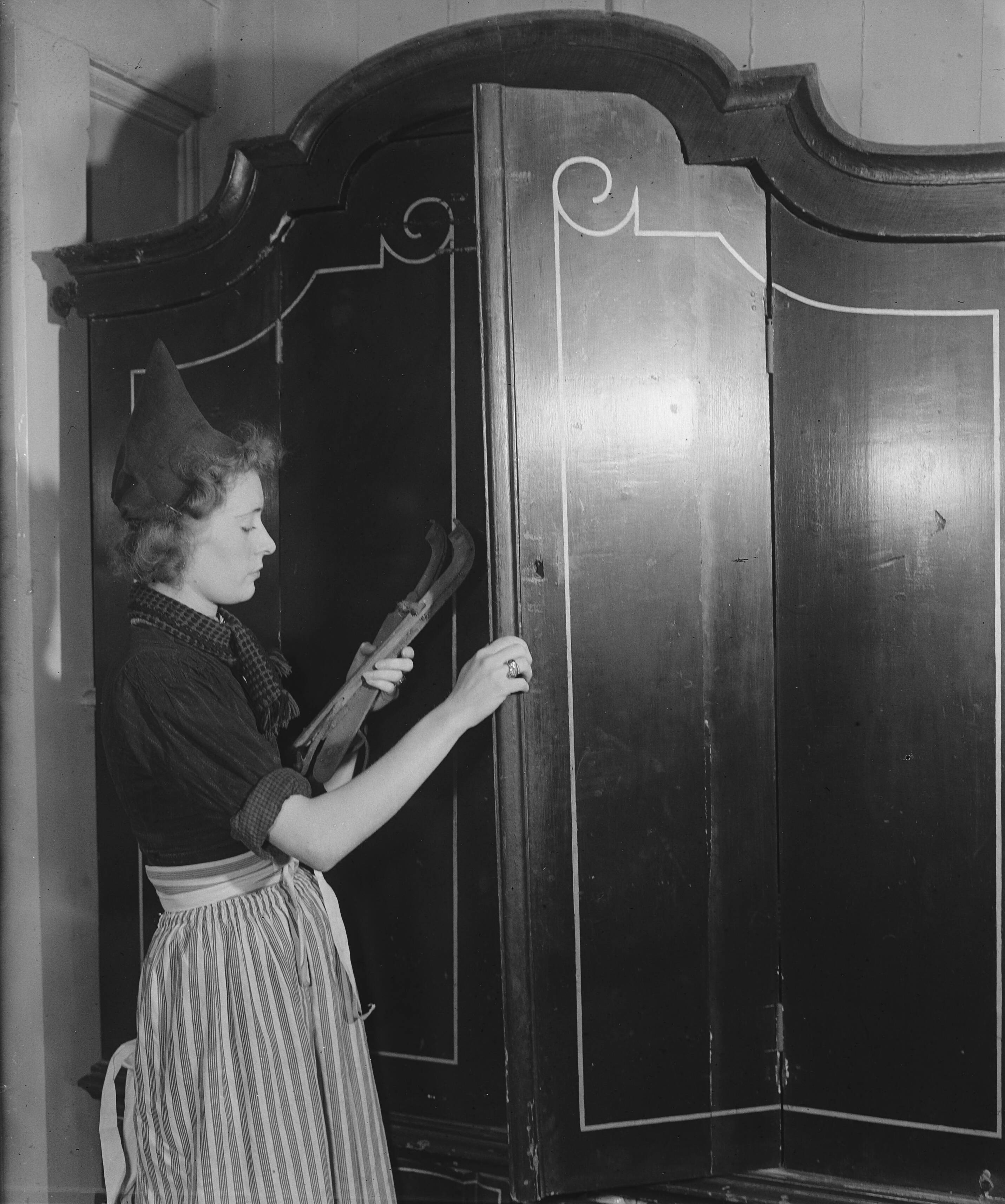 Volendam op de schaats — [vrouw haalt doorlopers uit de kast] — Foto: Raucamp, Koos / Anefo. Licentie: Set B: Rechtenvrij / Publiek Domein. Bron: Nationaal Archief. http://hdl.handle.net/10648/a8960298-d0b4-102d-bcf8-003048976d84