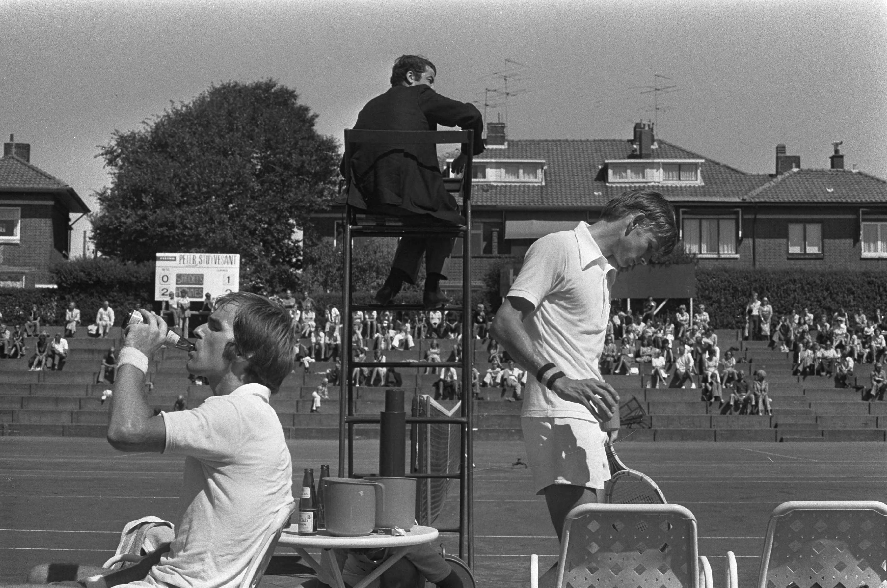 De finale van de Nationale tenniskampioenschappen op de METS-banen 1975 — Hemmes (l) en Sanders tijdens een pauze — Foto: Croes, Rob C. / Anefo. Licentie: Set B: Rechtenvrij / Publiek Domein. Bron: Nationaal Archief. http://hdl.handle.net/10648/ac6ff090-d0b4-102d-bcf8-003048976d84