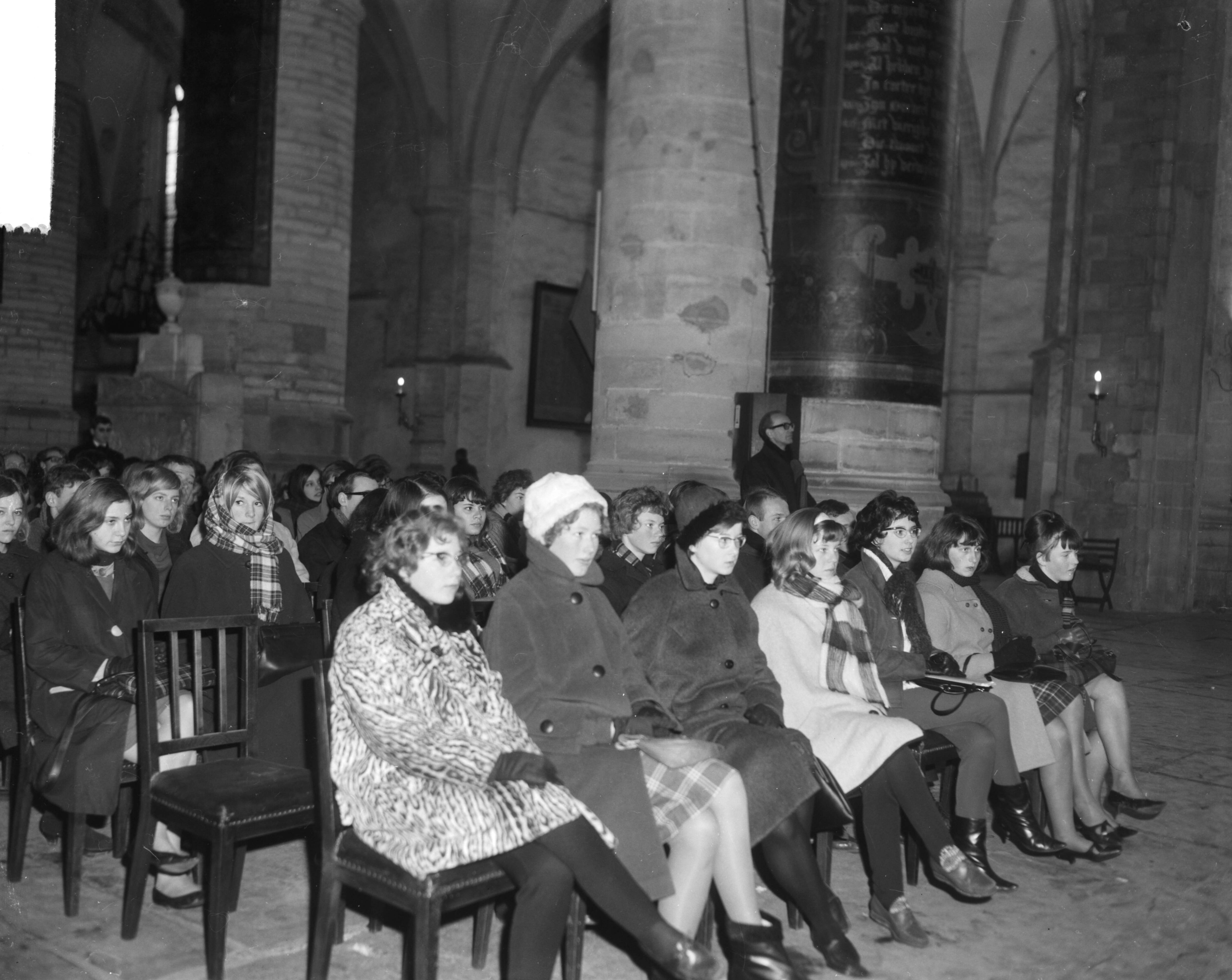 Fotocollectie Anefo — Hartewens Festival in de Sint Bavokerk te Haarlem geopend, aandachtig luistert de jeugd, gehuld in winterkleren — Foto: Bilsen, Joop van / Anefo. Licentie: Set B: Rechtenvrij / Publiek Domein. Bron: Nationaal Archief. http://hdl.handle.net/10648/aa8ac8e0-d0b4-102d-bcf8-003048976d84