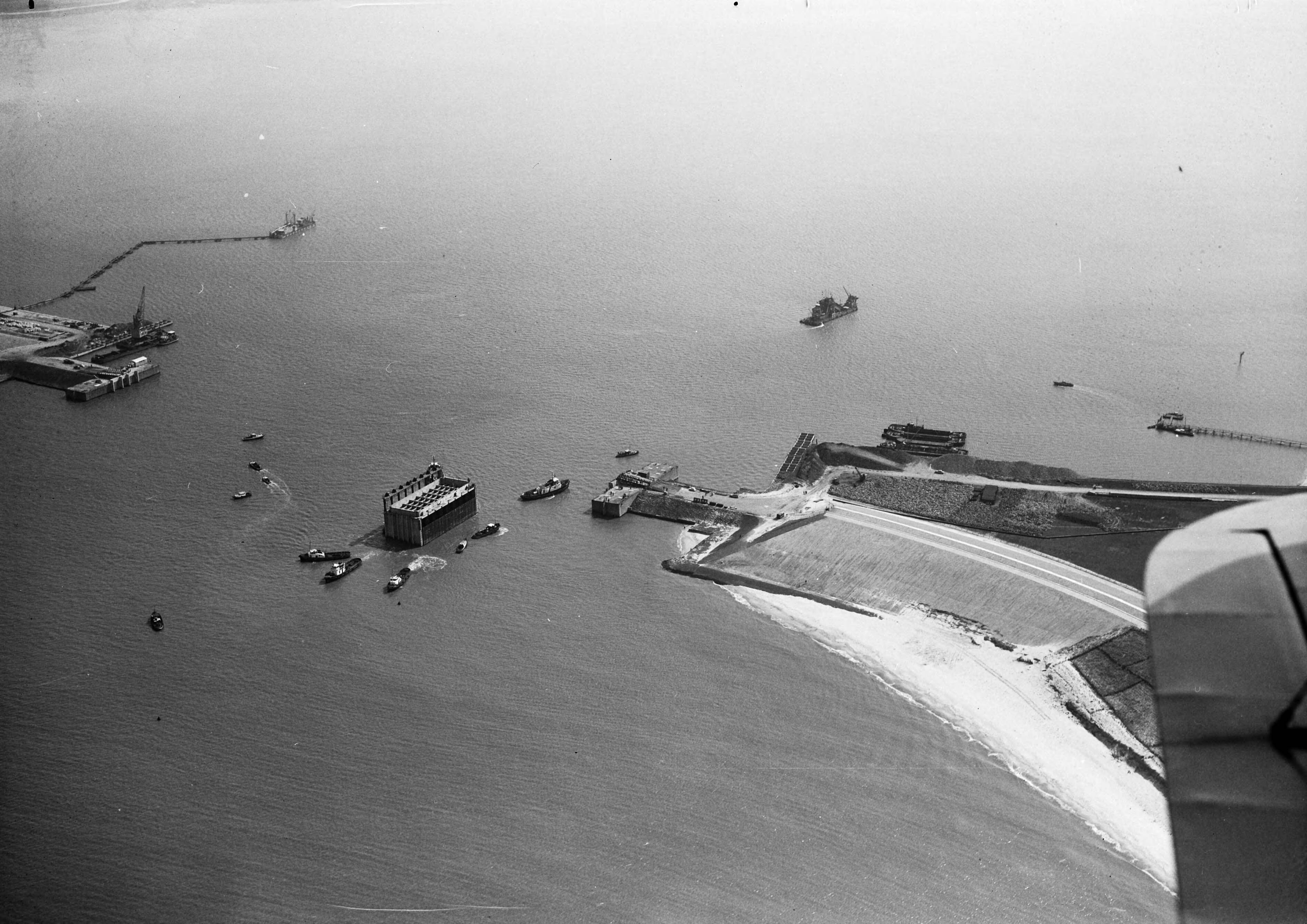 Fotocollectie Anefo — Luchtopnamen. Invaren van caissons in het Veerse Gat — Foto: Slagboom, Anton / Anefo. Licentie: Set B: Rechtenvrij / Publiek Domein. Bron: Nationaal Archief. http://hdl.handle.net/10648/a9d10f72-d0b4-102d-bcf8-003048976d84