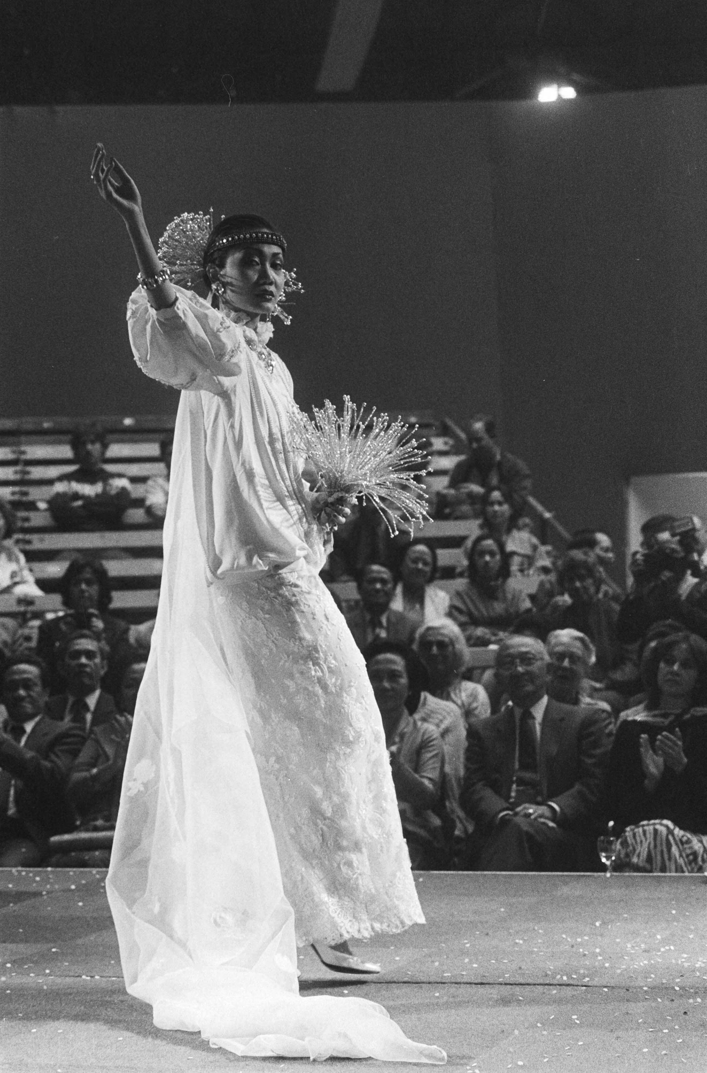 Fotocollectie Anefo — Opening Pasar Malam Besar in Den Haag ; een bruidsjurk tijdens de modeshow — Foto: Vollebregt, Sjakkelien / Anefo. Licentie: Set B: Rechtenvrij / Publiek Domein. Bron: Nationaal Archief. http://hdl.handle.net/10648/ad4817a4-d0b4-102d-bcf8-003048976d84