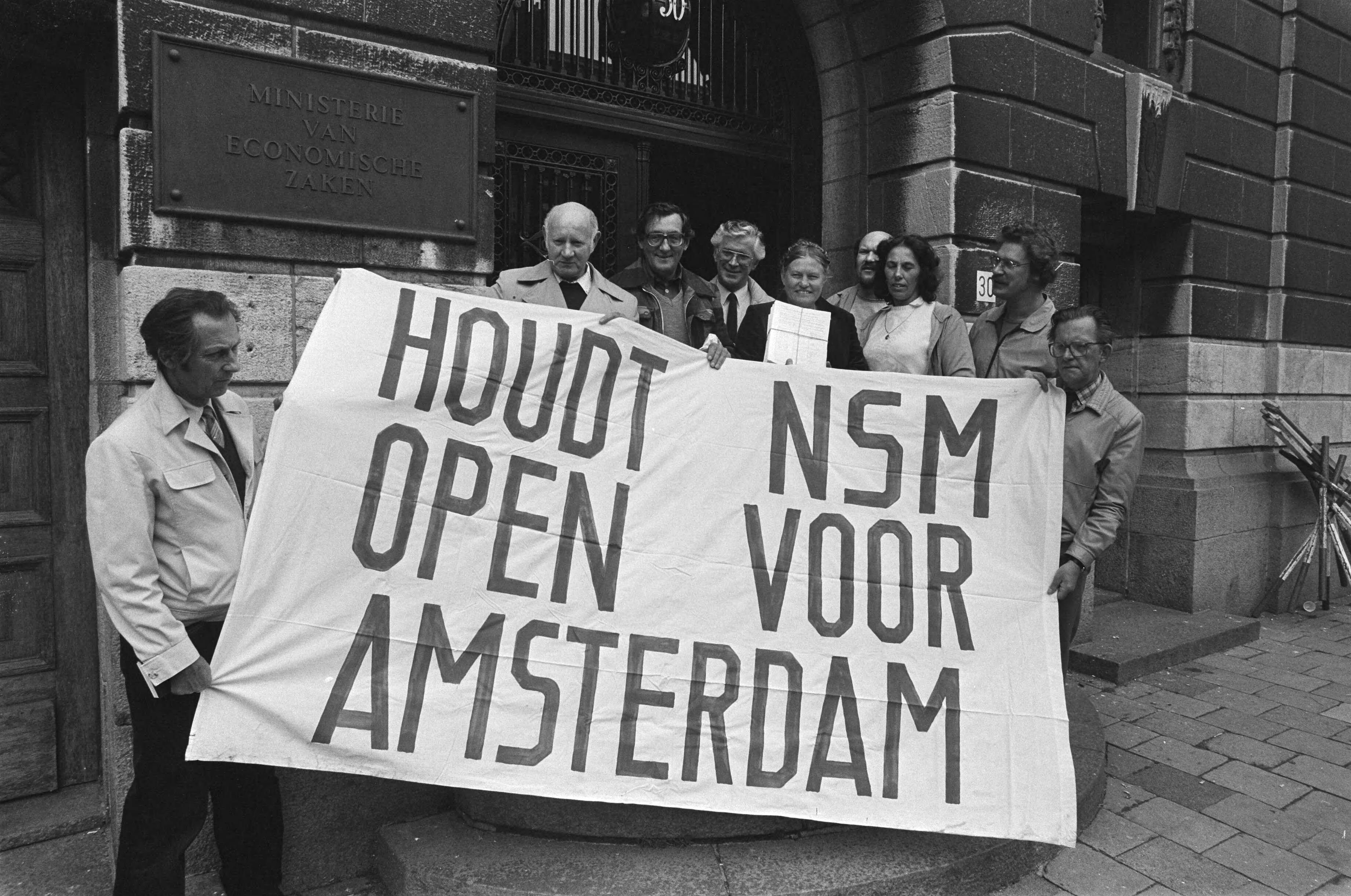 Fotocollectie Anefo — Personeel scheepswerf NSM, bieden handtekening aan op Economische Zaken Den Haag ; NSM-ers met spandoek voor de deur — Foto: Antonisse, Marcel / Anefo. Licentie: Set B: Rechtenvrij / Publiek Domein. Bron: Nationaal Archief. http://hdl.handle.net/10648/ad3932ac-d0b4-102d-bcf8-003048976d84