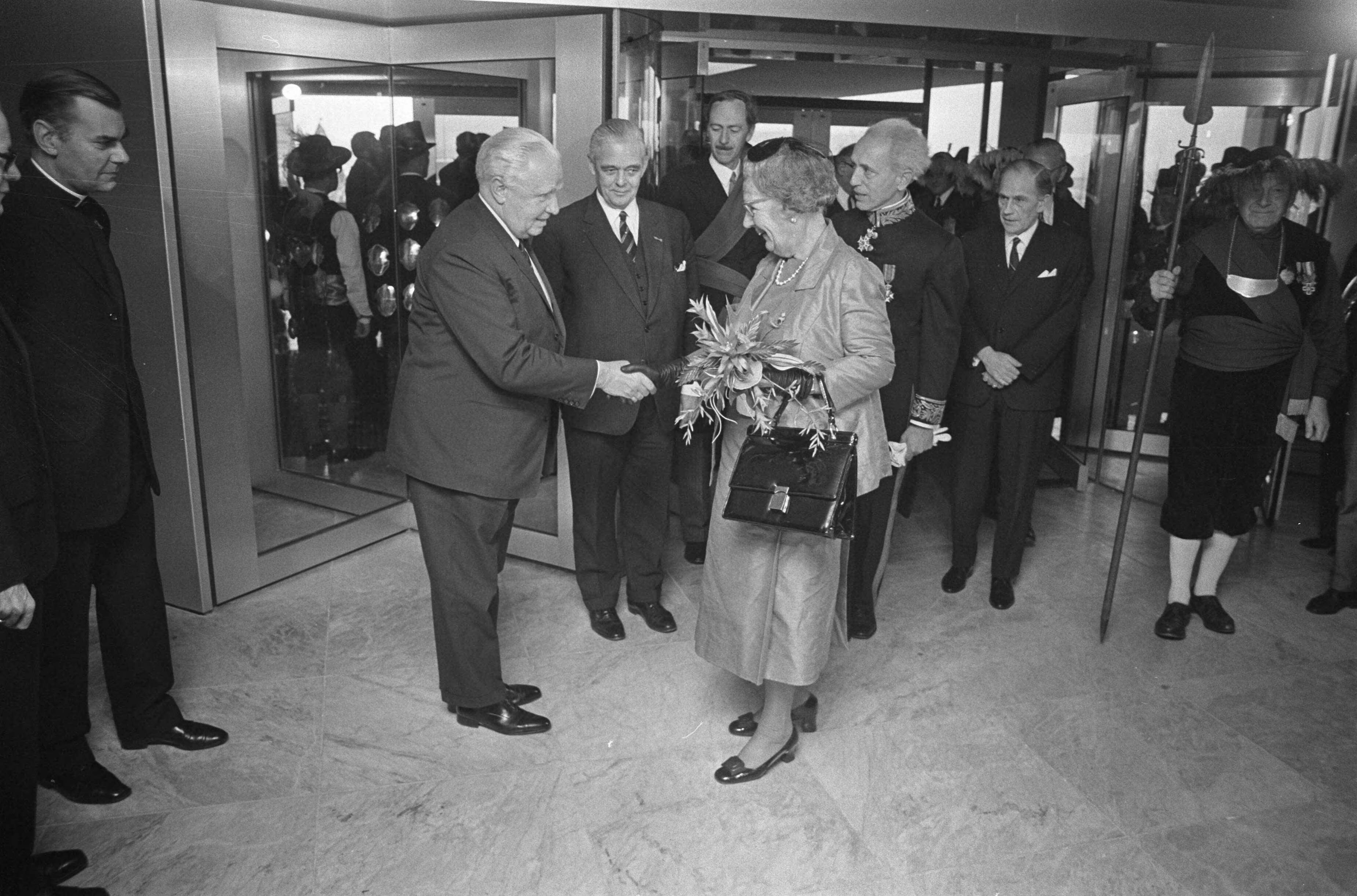 Koningin Juliana opent het nieuwe provinciehuis van Noord-Brabant in Den Bosch — Koningin Juliana schudt handen, hier met 2e kamervoorzitter mr. Van Thiel, tussen hen in Molly Geertsema, commissaris van de koningin in Gelderland, achter de koningin, commissaris van de Koningin in Noord-Brabant, C.N.M. Kortmann — Foto: Fotograaf Onbekend / Anefo. Licentie: Set B: Rechtenvrij / Publiek Domein. Bron: Nationaal Archief. http://hdl.handle.net/10648/abd6d5d6-d0b4-102d-bcf8-003048976d84