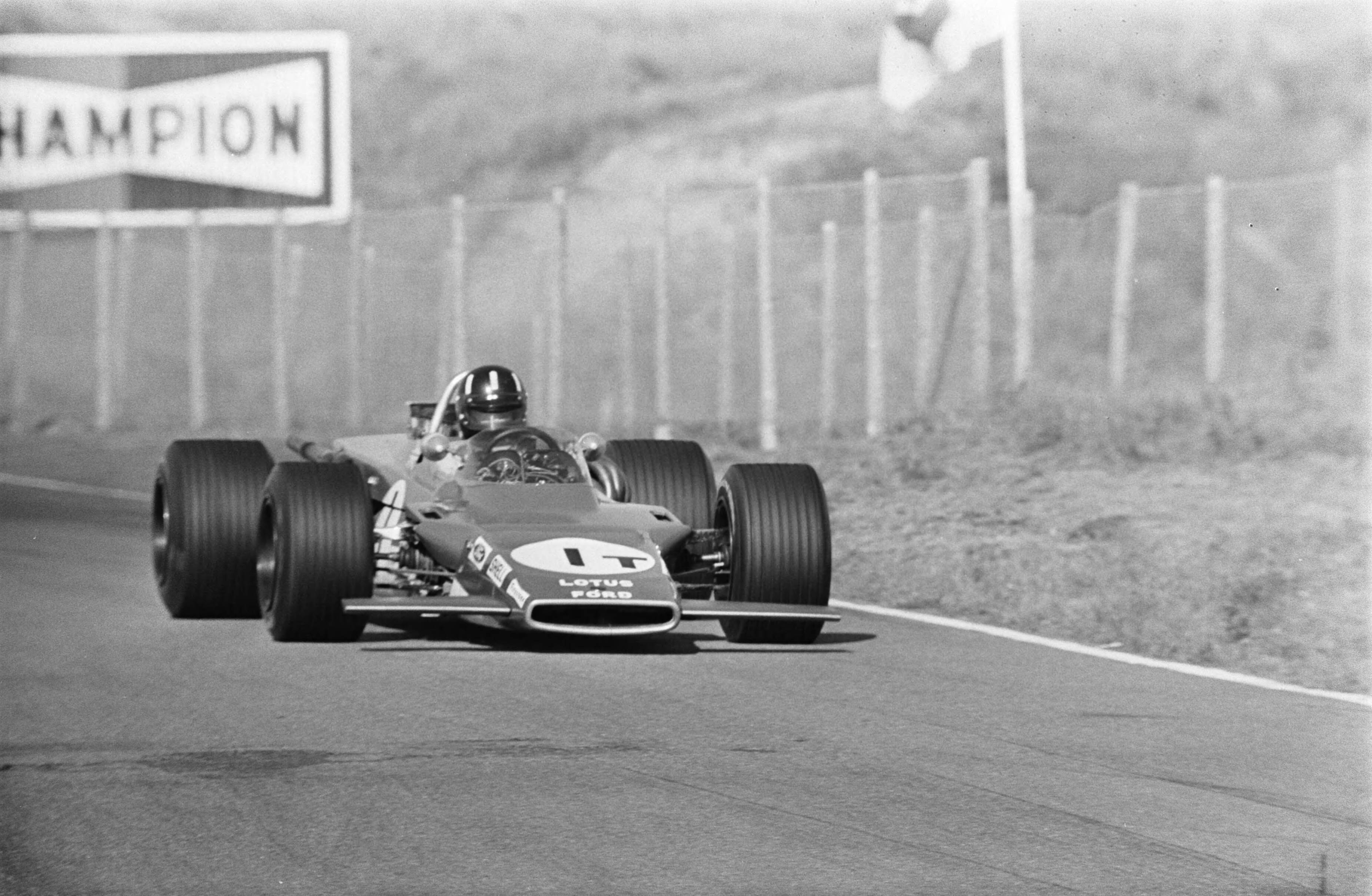 Grand Prix Zandvoort 1969 — Graham Hill in een Lotus met 4-wiel aandrijving in actie op de eerste trainingsdag — Foto: Fotograaf Onbekend / Anefo. Licentie: Set B: Rechtenvrij / Publiek Domein. Bron: Nationaal Archief. http://hdl.handle.net/10648/ab6f35c0-d0b4-102d-bcf8-003048976d84