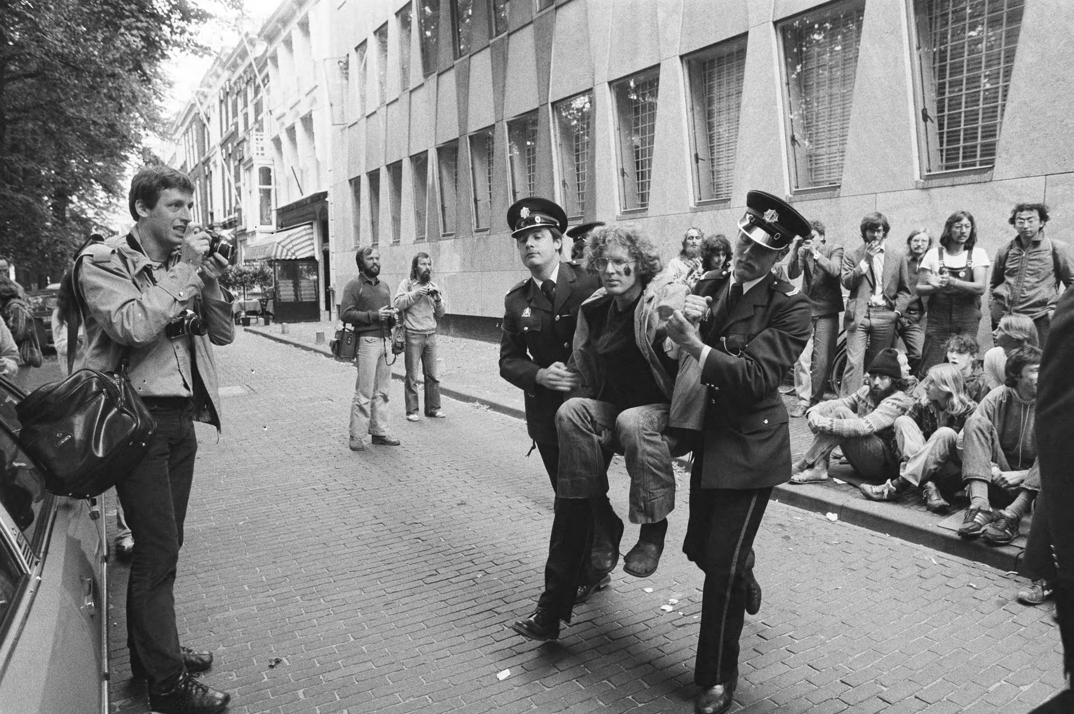 Demonstratie voor de VS-ambassade in Den Haag in verband met de productie van de neutronenbom — Politie draagt demonstranten weg — Foto: Dijk, Hans van / Anefo. Licentie: Set B: Rechtenvrij / Publiek Domein. Bron: Nationaal Archief. http://hdl.handle.net/10648/ad014ae0-d0b4-102d-bcf8-003048976d84