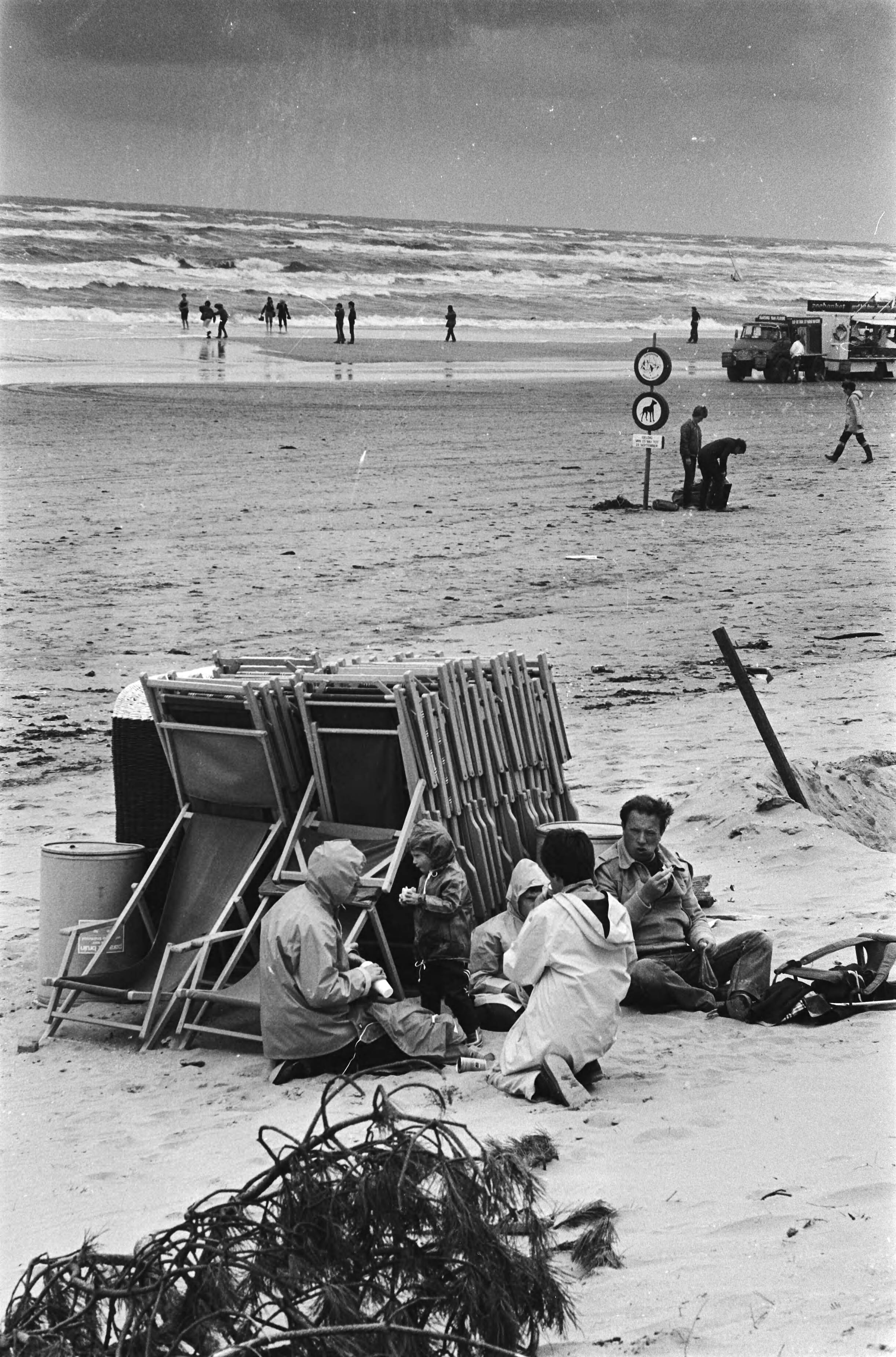 Slecht weer op Zandvoort — Mensen verscholen achter strandstoelen — Foto: Pereira, Fernando / Anefo. Licentie: Set B: Rechtenvrij / Publiek Domein. Bron: Nationaal Archief. http://hdl.handle.net/10648/ace43982-d0b4-102d-bcf8-003048976d84
