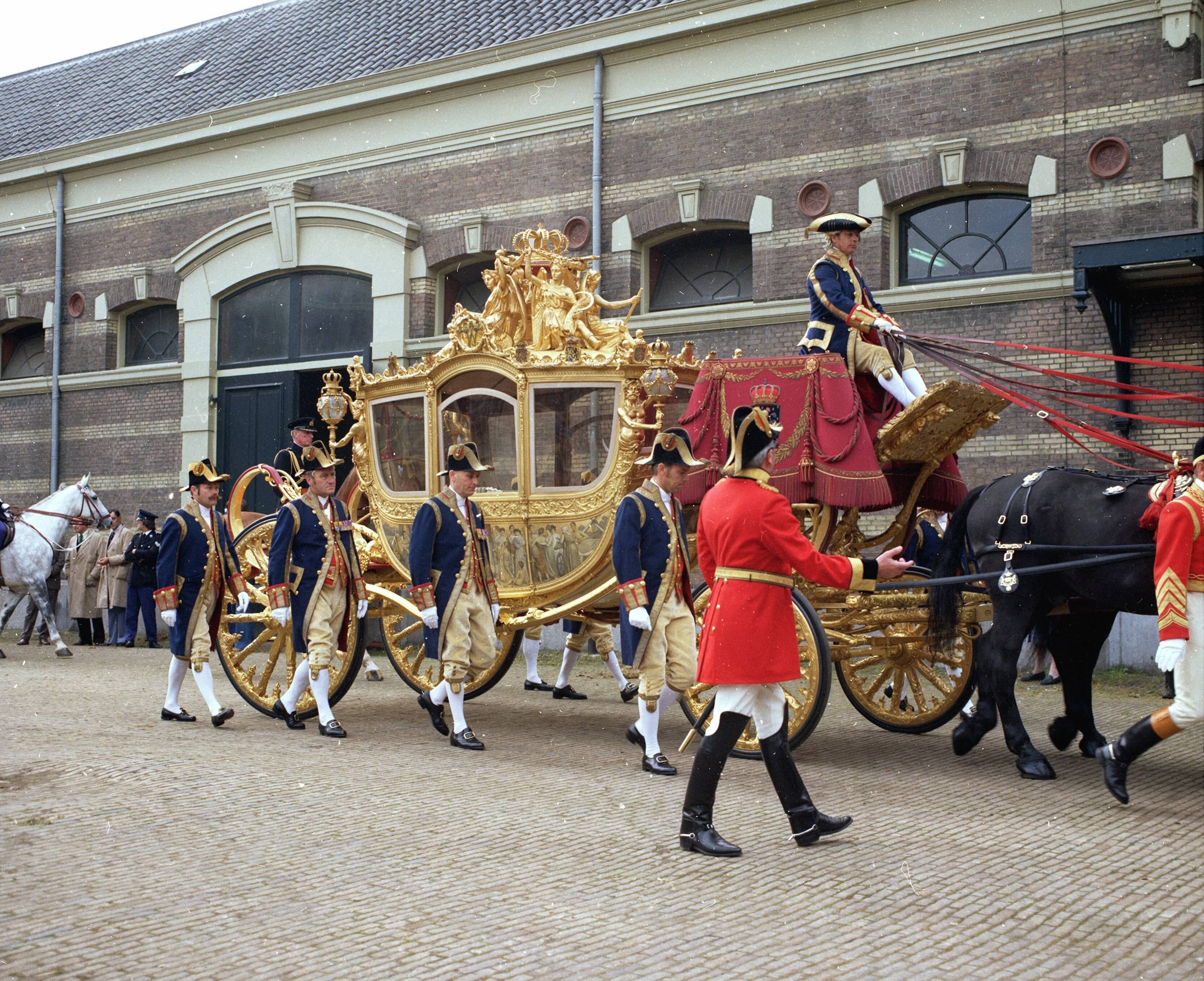 Fotocollectie RVD / Koninklijk Huis — Gouden koets met koetsier, stalpersoneel, lakeien en paarden op de binnenplaats van de koninklijke stallen aan de Noordwal in Den Haag — Foto: Mastenbroek, Cees / RVD. Licentie: Set B: Rechtenvrij / Publiek Domein. Bron: Nationaal Archief. http://hdl.handle.net/10648/afb278a4-d0b4-102d-bcf8-003048976d84
