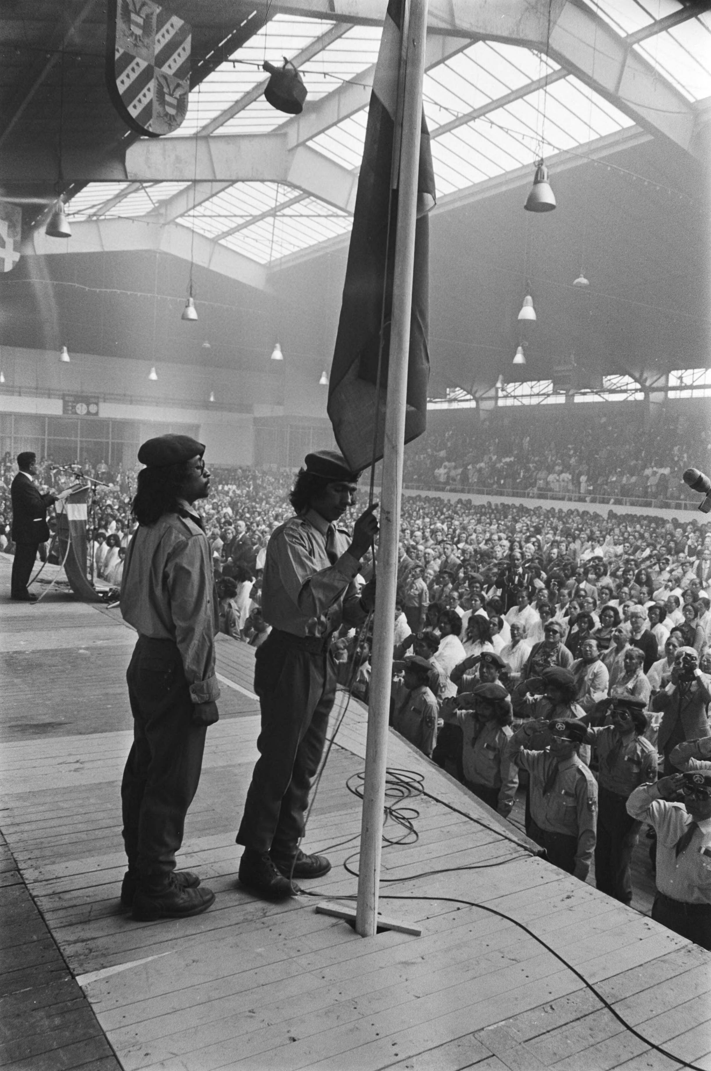 Fotocollectie Anefo — Herdenking Zuidmolukse onafhankelijkheidsproclamatie in Houtrusthallen, Den Haag ; hijsen van de vlag — Foto: Bogaerts, Rob / Anefo. Licentie: Set B: Rechtenvrij / Publiek Domein. Bron: Nationaal Archief. http://hdl.handle.net/10648/ac82120c-d0b4-102d-bcf8-003048976d84