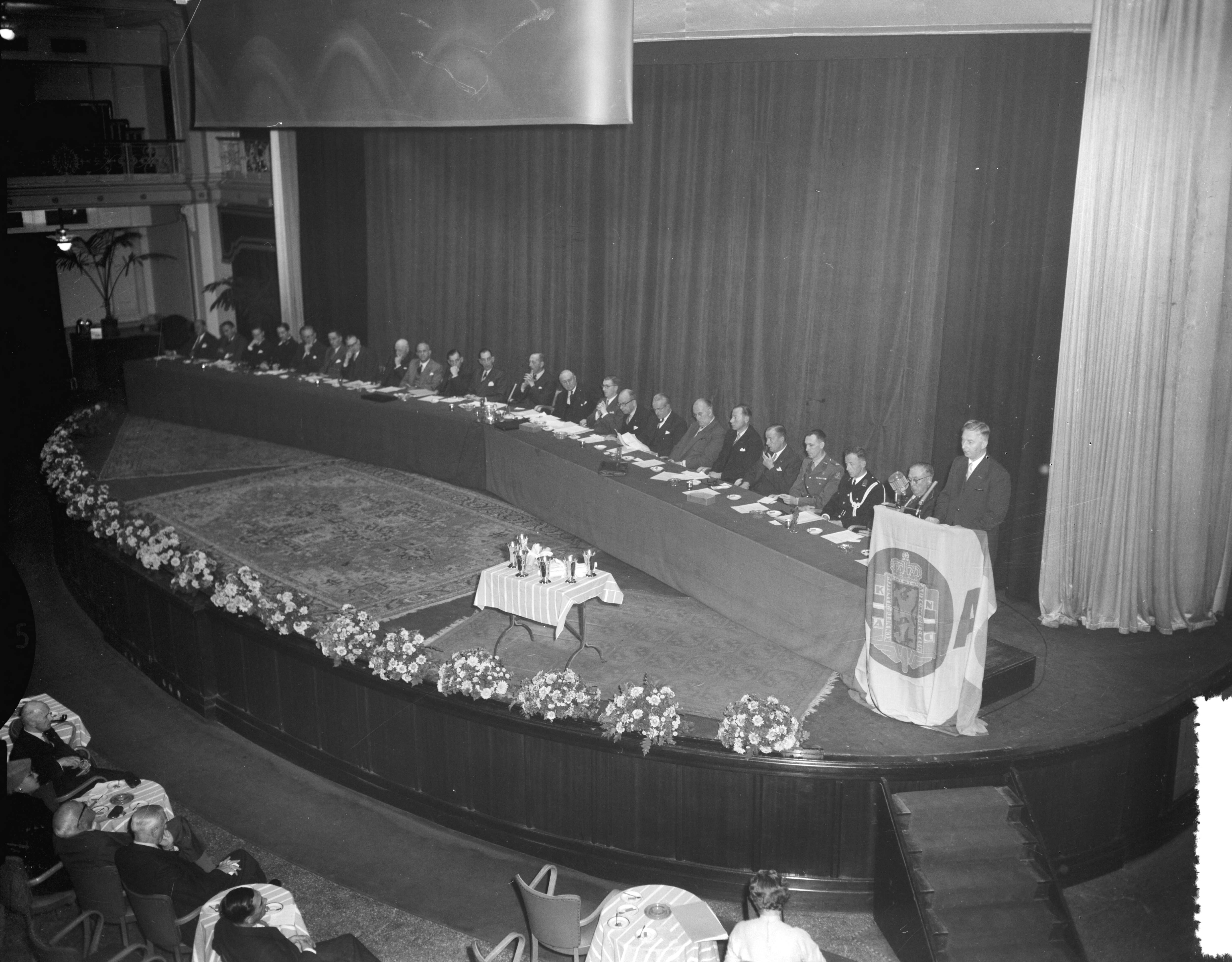 Fotocollectie Anefo — Opening Wegverkeersdag van het KNAC in het Kurhaus te Scheveningen. Openingstoespraak door minister J. Algera met overzicht bestuurstafel — Foto: Bilsen, Joop van / Anefo. Licentie: Set B: Rechtenvrij / Publiek Domein. Bron: Nationaal Archief. http://hdl.handle.net/10648/a9526d20-d0b4-102d-bcf8-003048976d84