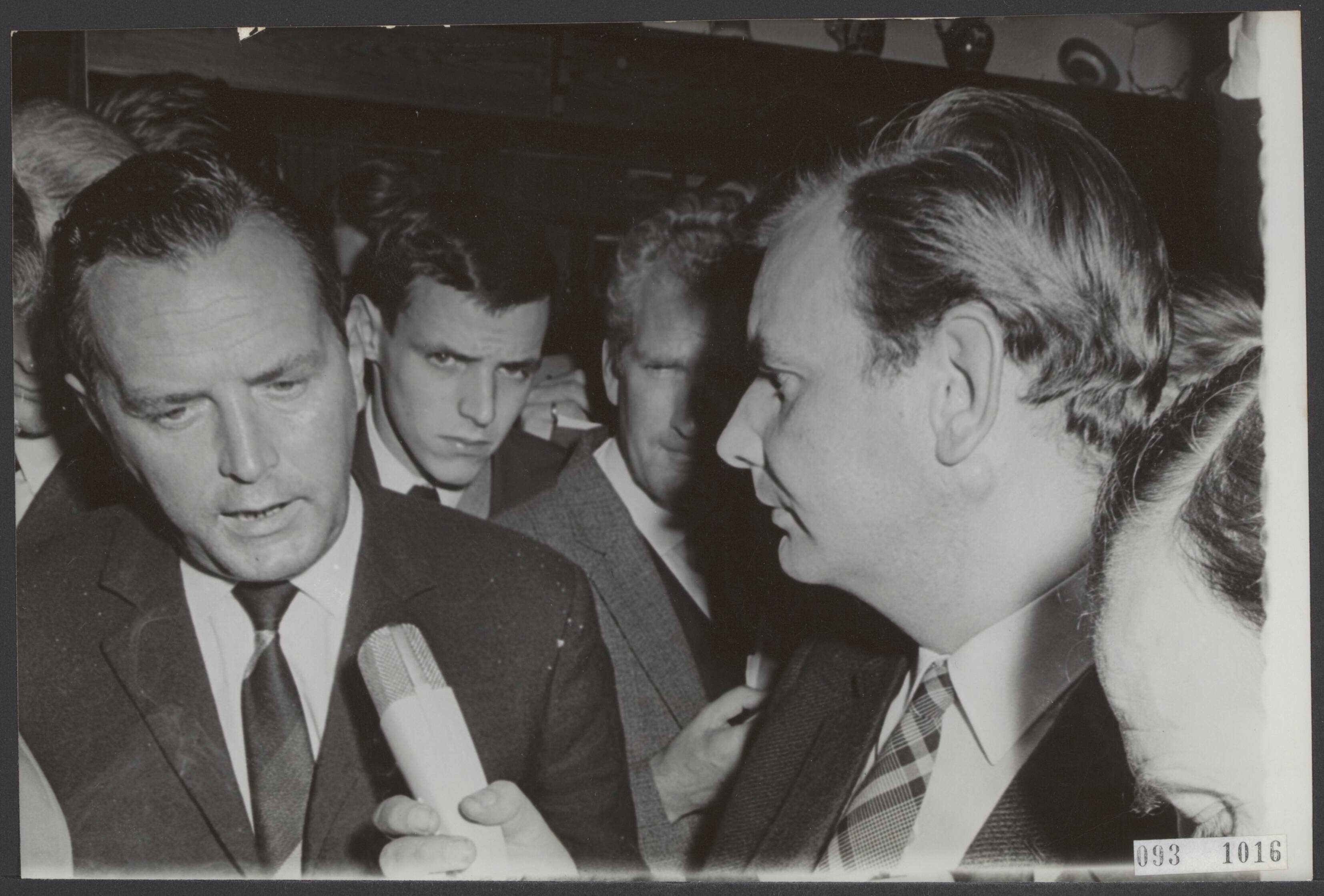 Fotocollectie Elsevier Binnenland — De noodraad van de Boerenpartij is in Blaricum bijeengekomen i.v.m. de zaak ir. Adams. Ir. Stam (statenlid) wordt hier geiterviewd door TV-verslaggever Frits van der Poel, nadat hij de zaal even voor het einde der vergadering had verlaten — Foto: Nijs, Jac. de / Anefo. Licentie: Set B: Rechtenvrij / Publiek Domein. Bron: Nationaal Archief. http://hdl.handle.net/10648/ae29f4e4-d0b4-102d-bcf8-003048976d84