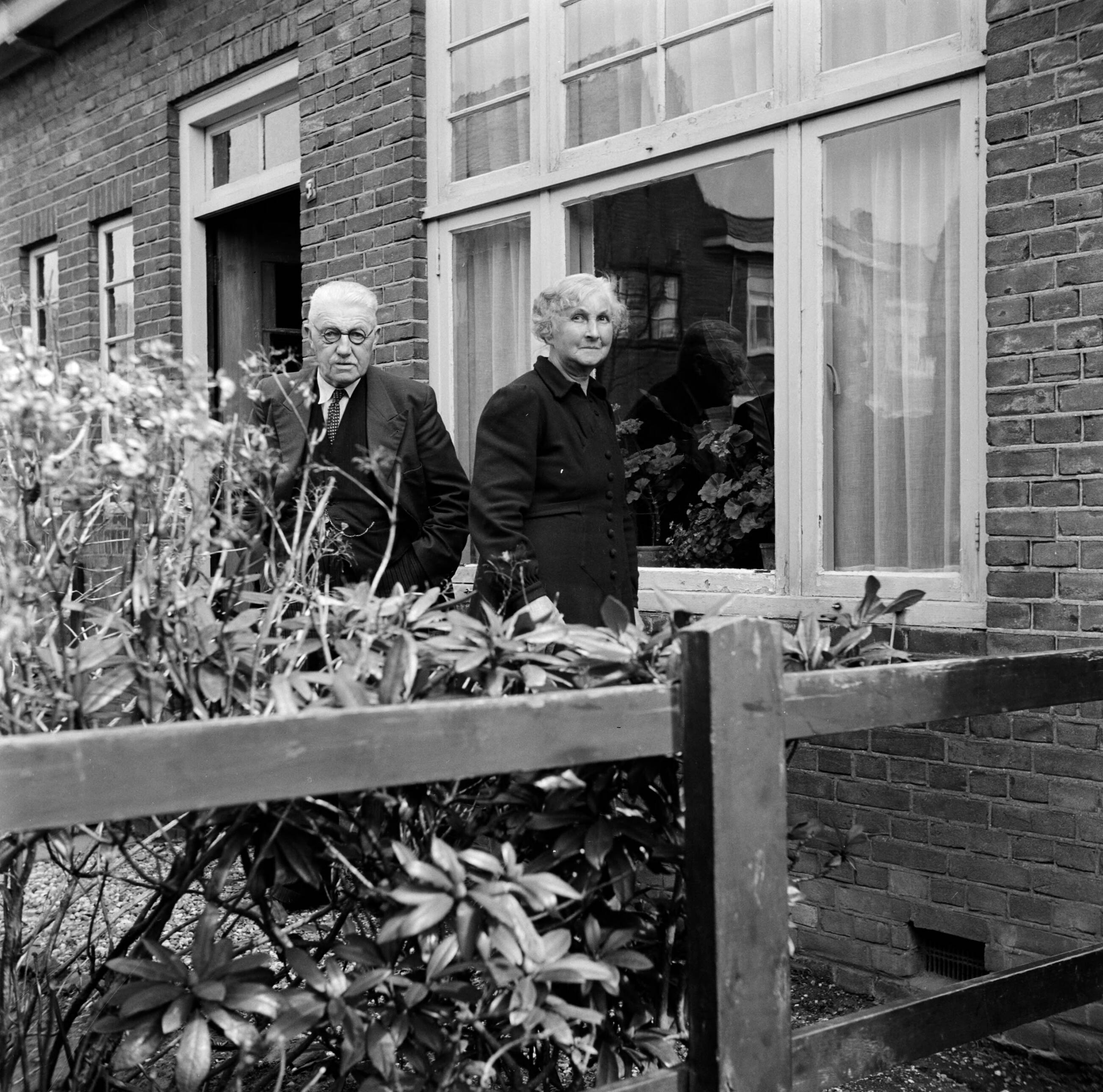 Fotocollectie Van de Poll — Het echtpaar S. de Jong in de tuin voor hun woning in het Friese Huizum (nu deel van Leeuwarden) — Foto: Poll, Willem van de. Licentie: Set B: Rechtenvrij / Publiek Domein. Bron: Nationaal Archief. http://hdl.handle.net/10648/aeccc390-d0b4-102d-bcf8-003048976d84