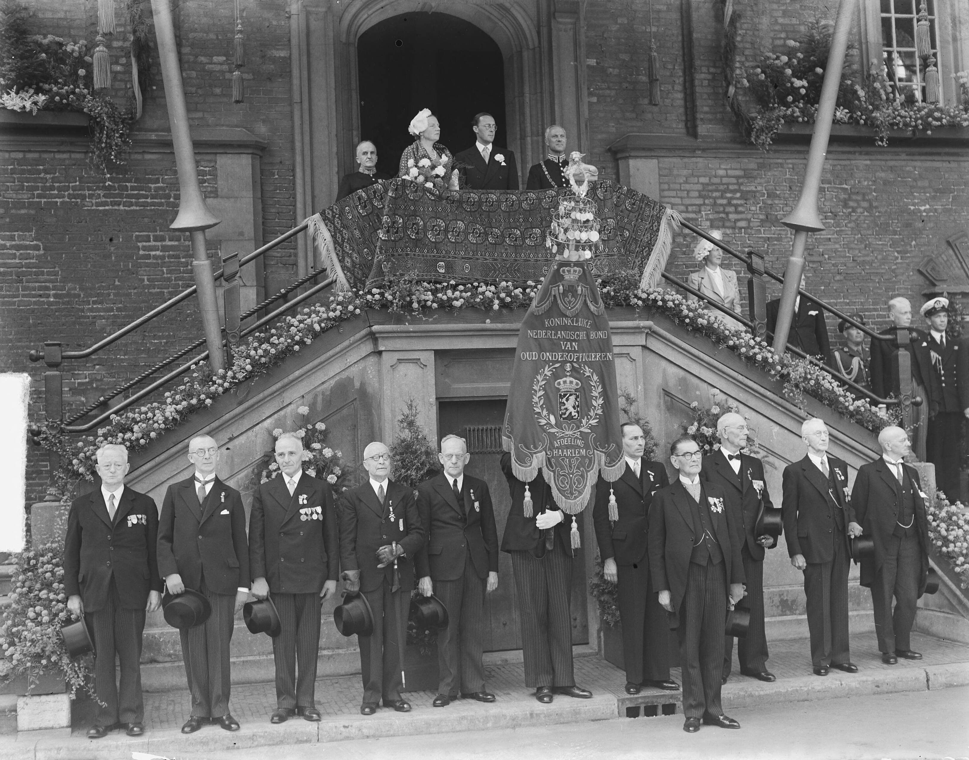 Koningin Juliana en prins Bernhard in Haarlem — Koningin Juliana en prins Bernhard op het bordes van het raadhuis — Foto: Bilsen, Joop van / Anefo. Licentie: Set B: Rechtenvrij / Publiek Domein. Bron: Nationaal Archief. http://hdl.handle.net/10648/a8cb2892-d0b4-102d-bcf8-003048976d84
