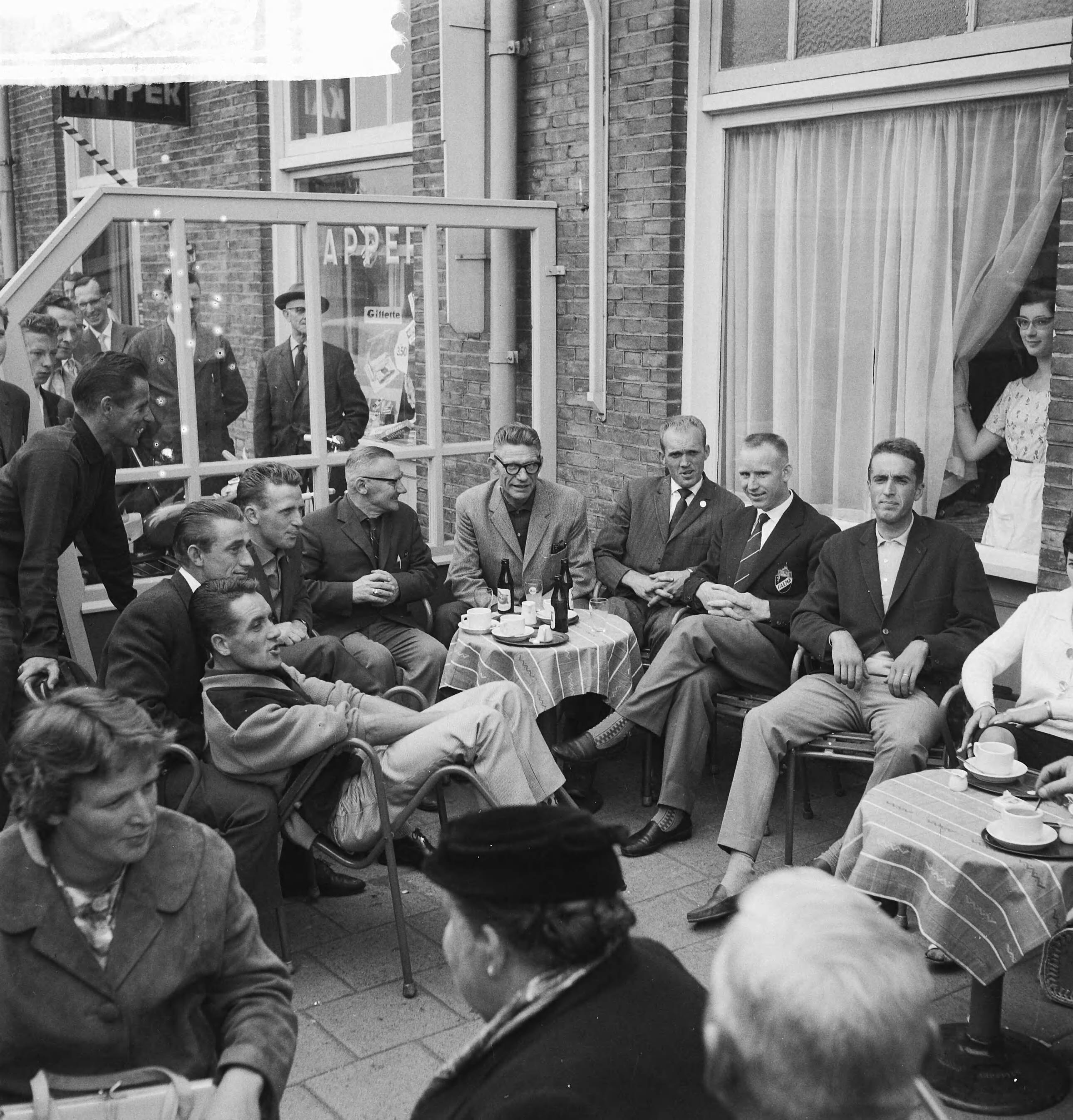 Tour de France 1961 — Vertrek Tour de France ploeg naar Frankrijk. De renners en officials op het terras. Zittend vlnr. Piet Damen, Wout Wagtmans, Jaap Kersten, verzorger, ploegleider Klaas Buchly, Coen Niesten, Piet van Est en Ab Geldermans. Staand links Jef Lahaye — Foto: Koch, Eric / Anefo. Licentie: Set B: Rechtenvrij / Publiek Domein. Bron: Nationaal Archief. http://hdl.handle.net/10648/a9d9a402-d0b4-102d-bcf8-003048976d84