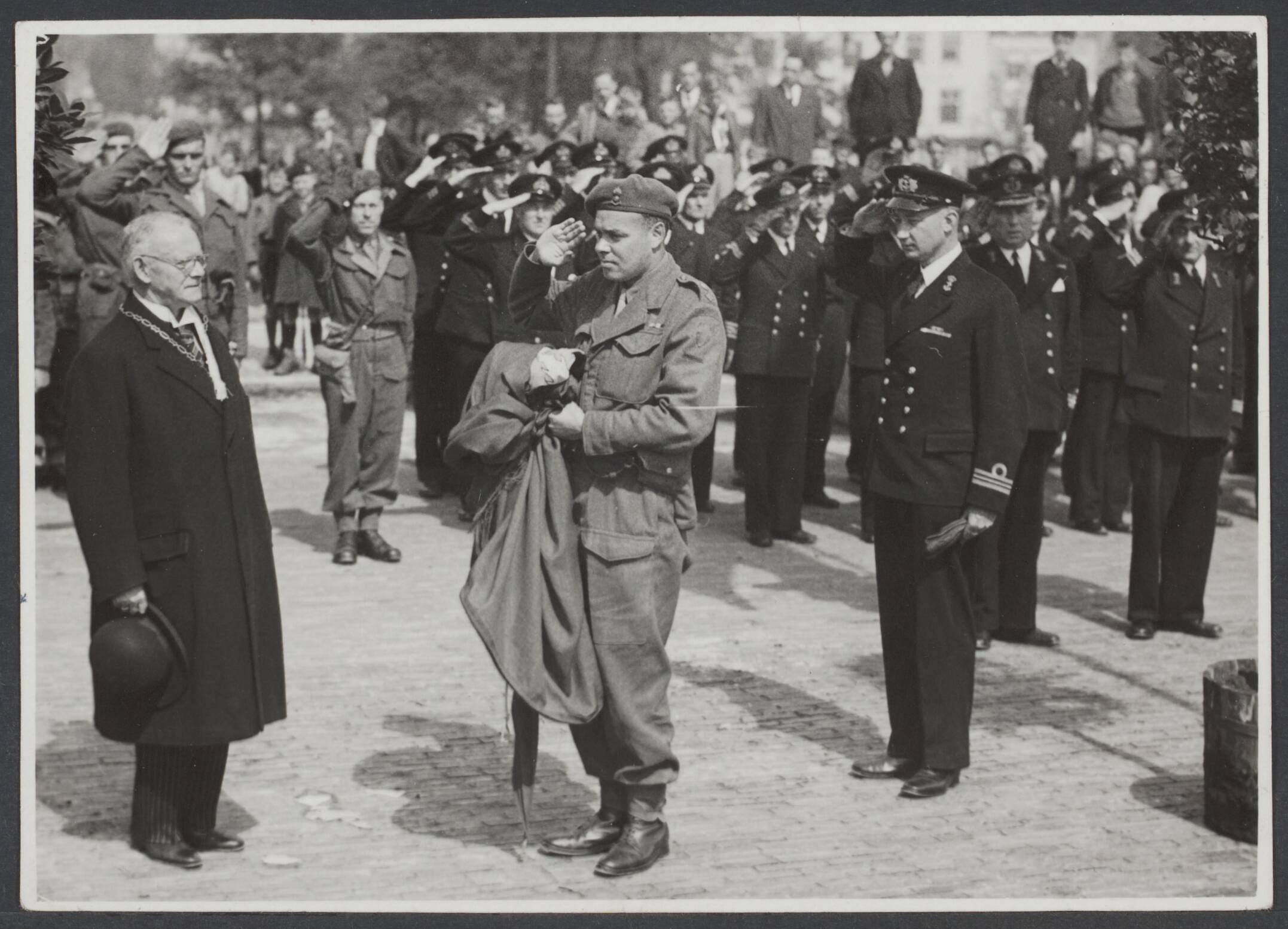 Bevrijding Nederland 1944 [bevat ook foto's uit 1945] — Na lijden komt verblijden. De vredesfeesten zijn enthousiast gevierd in Vlissingen. Als hoogtepunt had de overdracht plaats van de Vlissingse vlag voor de troepen die bij de bevrijding van de stad het dapperst hadden gestreden. 't was de laatste officiële plechtigheid die door de heer Van Woelderen als burgemeester van Vlissingen werd verricht. Tegen 1 juli heeft deze eminente magistraat na een ambtsperiode van 26 jaar eervol ontslag gevraagd om gezondheidsredenen op advies van zijn behandelend geneesheer — Foto: Dellaert, J.F. / Spaarnestad. Licentie: Set B: Rechtenvrij / Publiek Domein. Bron: Nationaal Archief. http://hdl.handle.net/10648/48348fec-7024-24e3-d97d-56caa9ffb33c