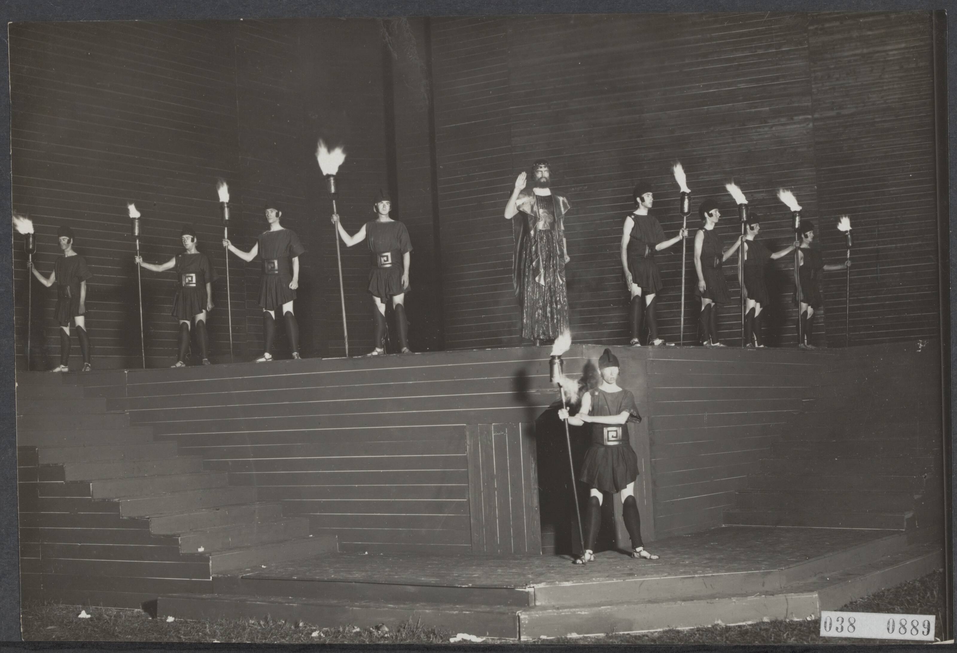 Fotocollectie Elsevier Binnenland — Lustrumfeesten in Groningen. Openluchtvoorstelling van het Griekse treurspel "Antigone". Scene: de koning en zijn fakkeldragers — Foto: Kramer, Piet. Licentie: Set B: Rechtenvrij / Publiek Domein. Bron: Nationaal Archief. http://hdl.handle.net/10648/adf2c29e-d0b4-102d-bcf8-003048976d84