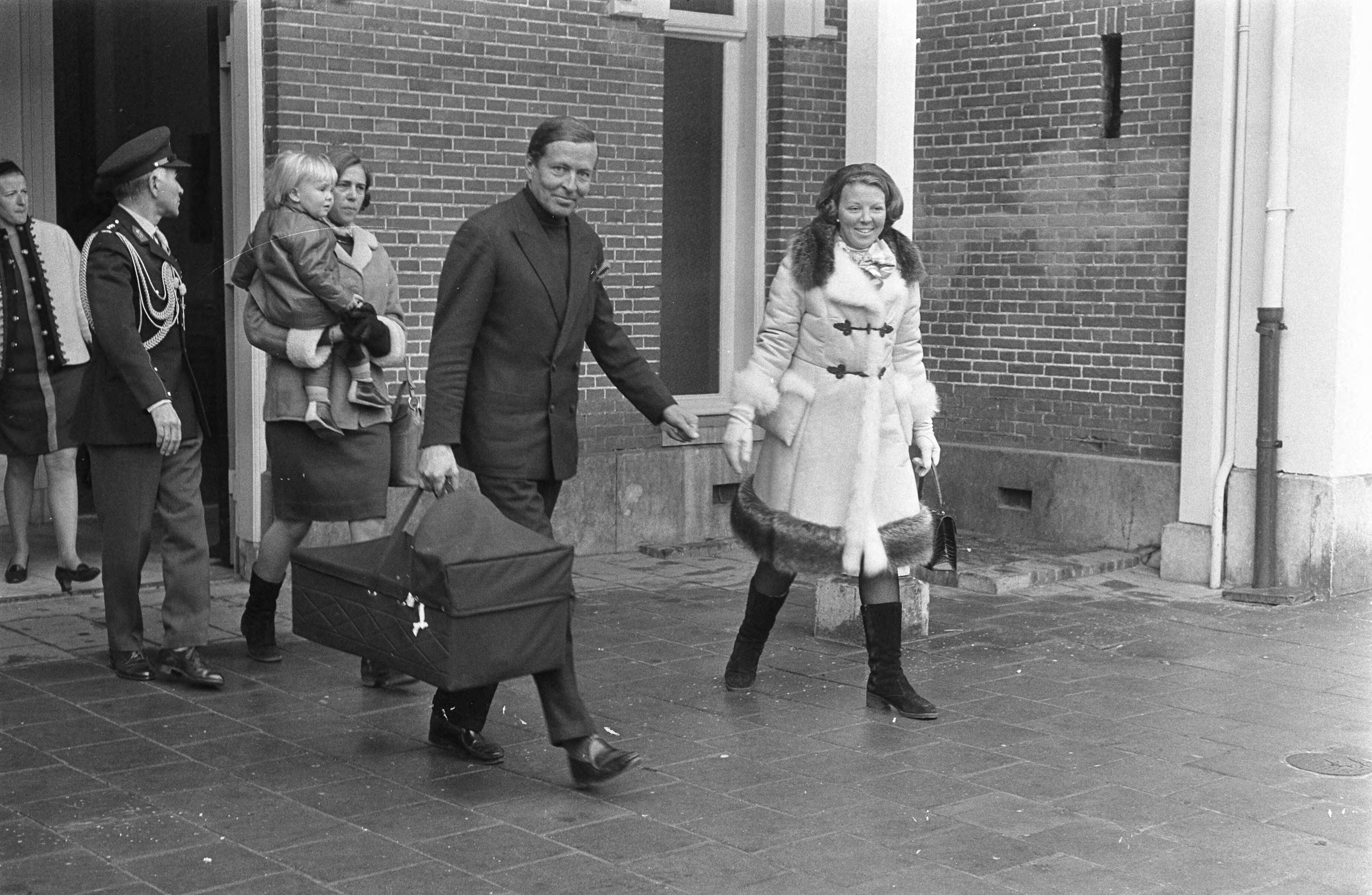 Fotocollectie Anefo — Koninklijke familie terug uit Lech, op station Baarn Prins Claus en Prinses Beatrix dragen reiswieg, op achtergrond Schwellengrebel met Prins Willem Alexander — Foto: Koch, Eric / Anefo. Licentie: Set B: Rechtenvrij / Publiek Domein. Bron: Nationaal Archief. http://hdl.handle.net/10648/ab633c7a-d0b4-102d-bcf8-003048976d84