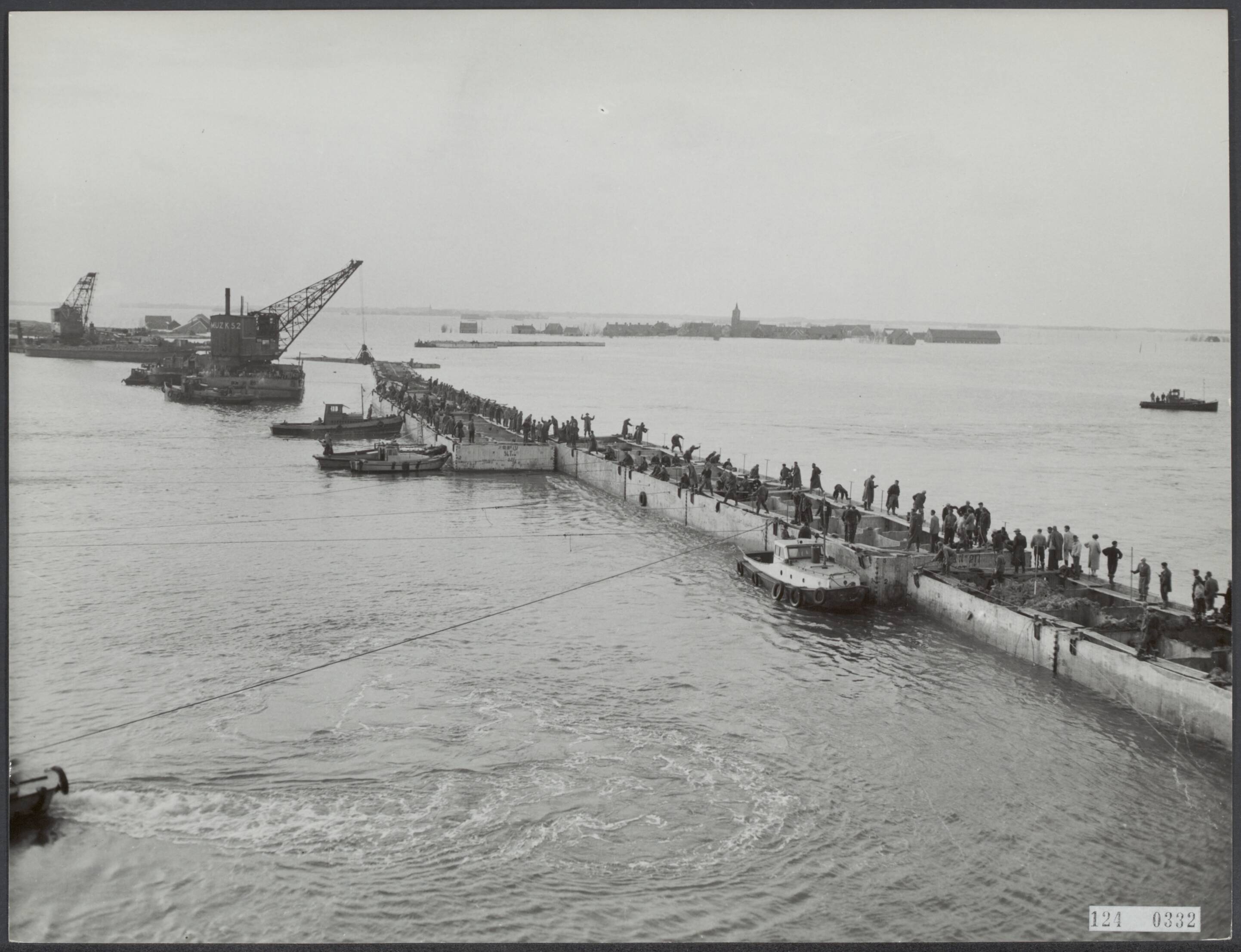 Overstromingen / Watersnoodramp 1953 / Herstel [RVD] — Laatste opening in ooster inlaagdijk bij Schelphoek dicht. Donderdagavond, om 10 minuten over half zeven is de laatste opening in de ooster inlaagdijk bij Schelphoek gesloten. Dit geschiedde met twaalf caissons, die in twee elementen tegelijk werden geplaatst. De sluiting werd bijgewoond door talrijke autoriteiten. Het moment waarop de stroomgat wordt afgesloten. Op de achtergrond Serooskerke. — Foto: ANP / RVD of rechtenvrij. Licentie: Set B: Rechtenvrij / Publiek Domein. Bron: Nationaal Archief. http://hdl.handle.net/10648/af31c88a-d0b4-102d-bcf8-003048976d84